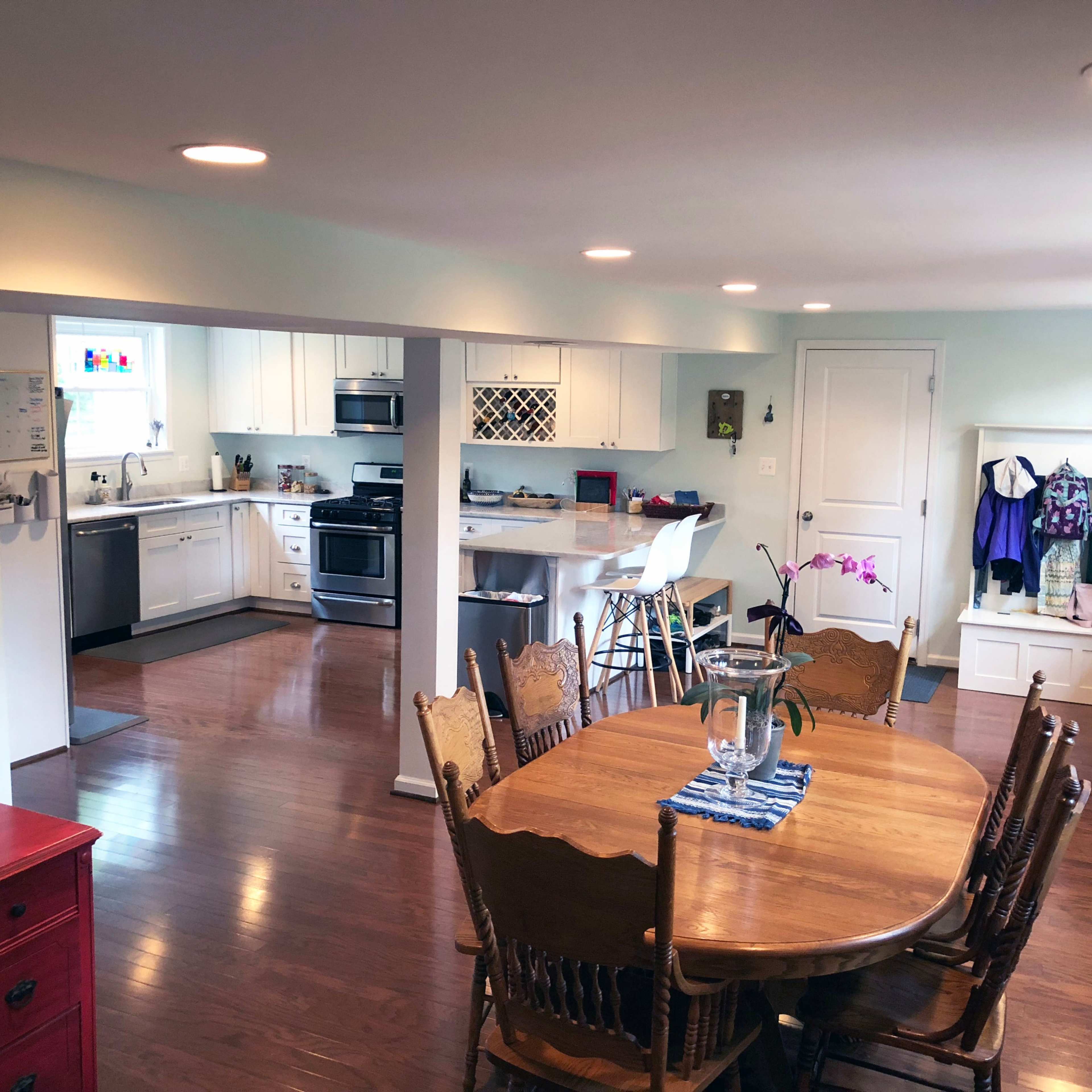 A brightly lit open-concept kitchen and dining area featuring a wooden dining table, beige walls, and modern appliances.