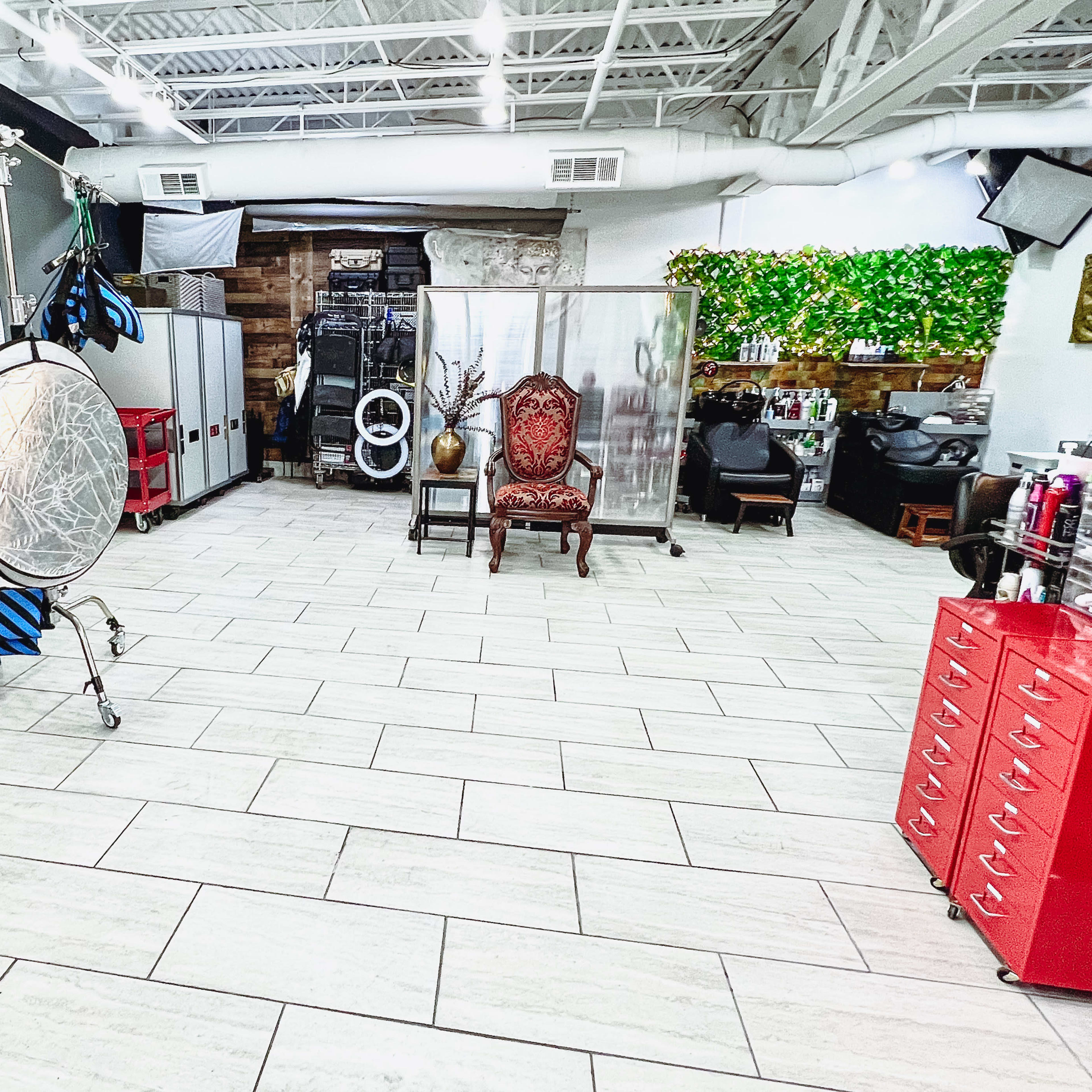 A spacious salon interior with a mix of styling equipment, a large mirror, and a decorative antique chair.