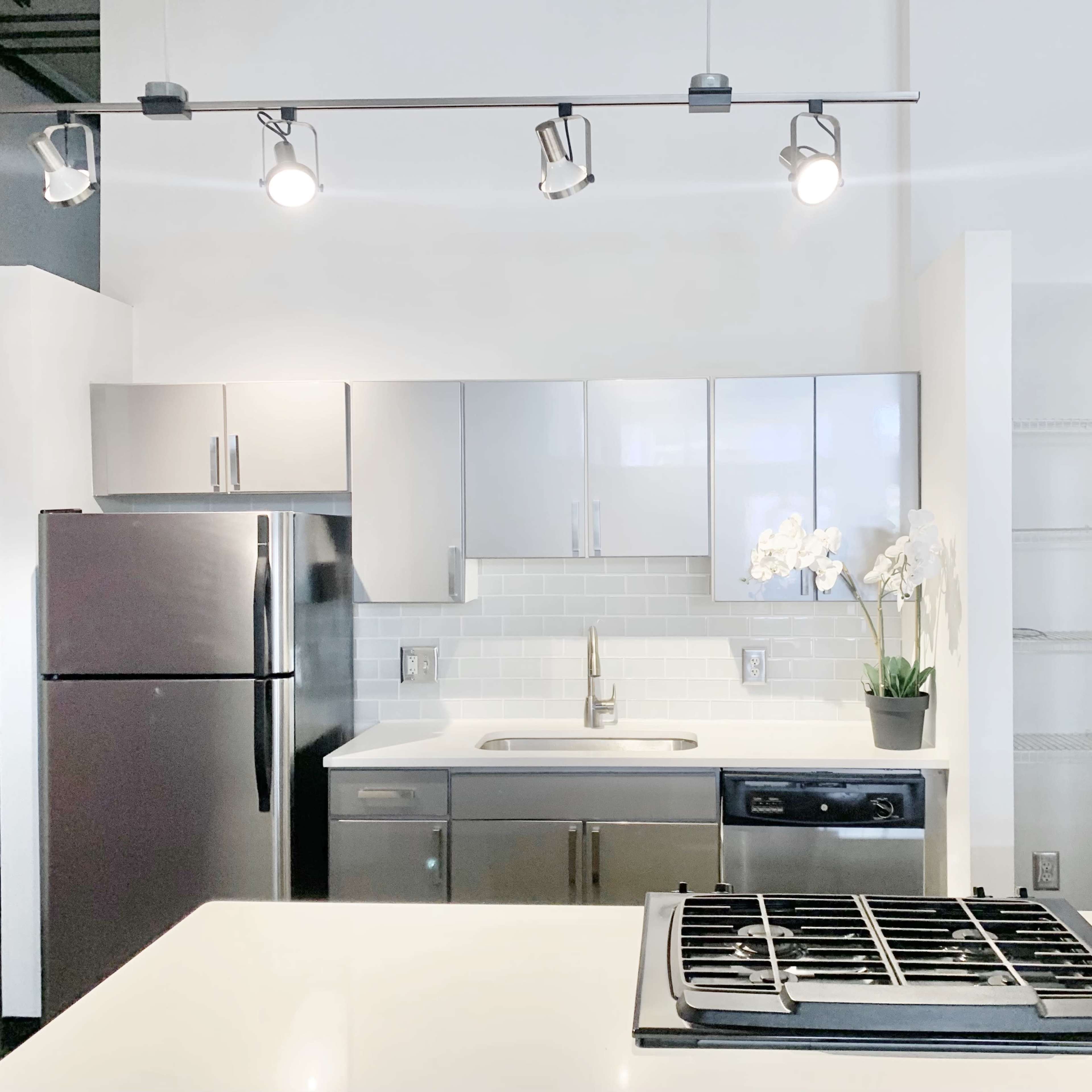 A modern kitchen with stainless steel appliances, a white countertop, and sleek cabinetry.