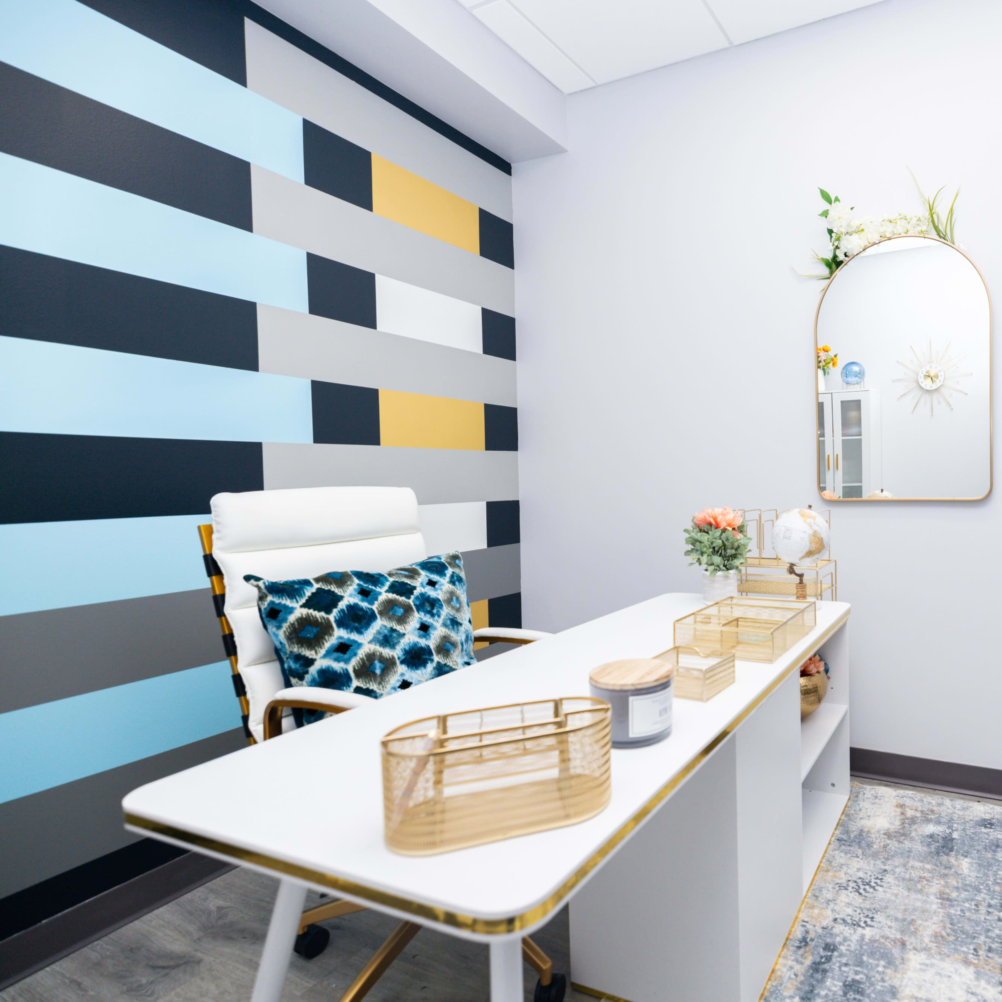 A modern office space features a minimalist desk, a round mirror, and patterned walls in blue and gray tones.