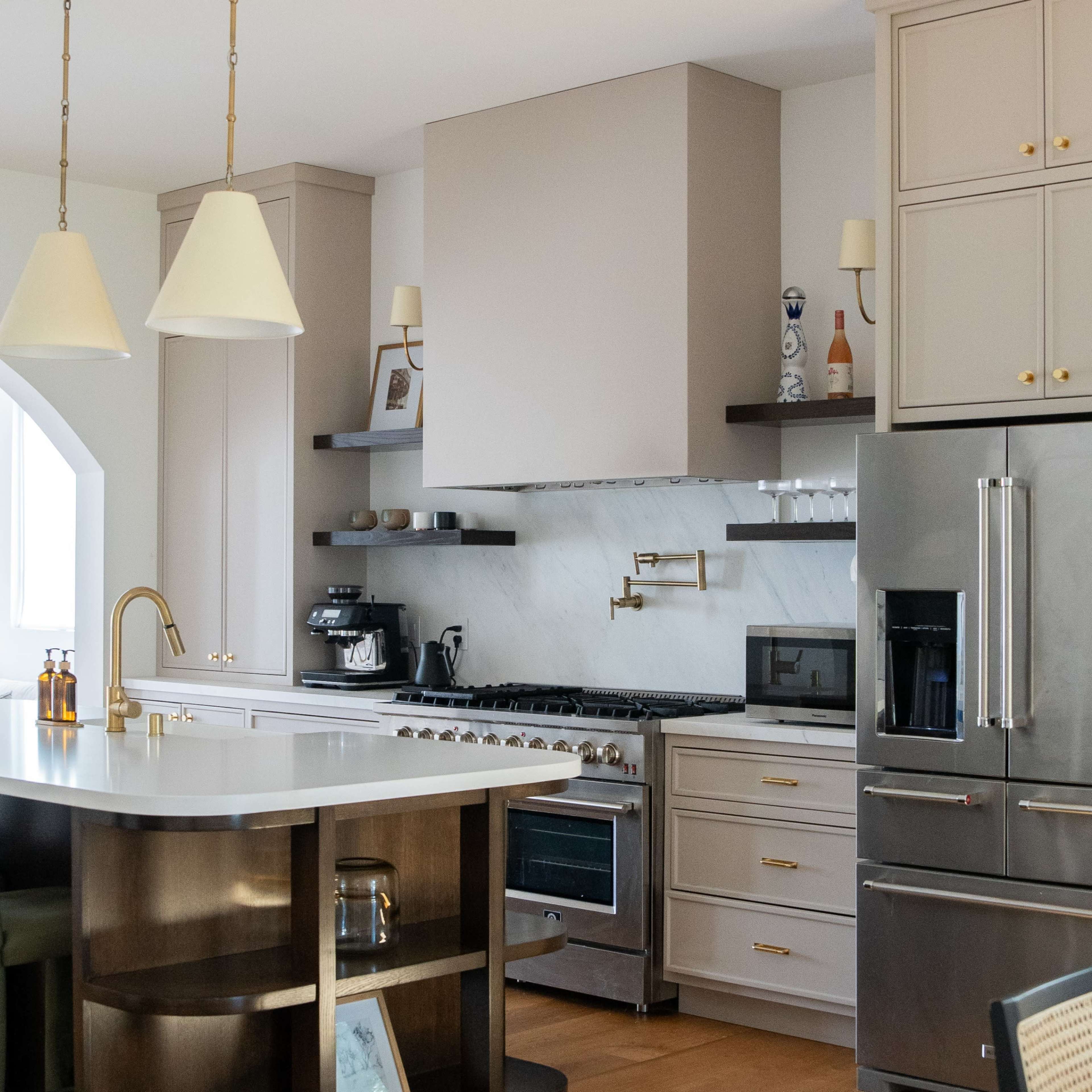 A modern kitchen featuring a large island with a white countertop, stainless steel appliances, and wooden accents.