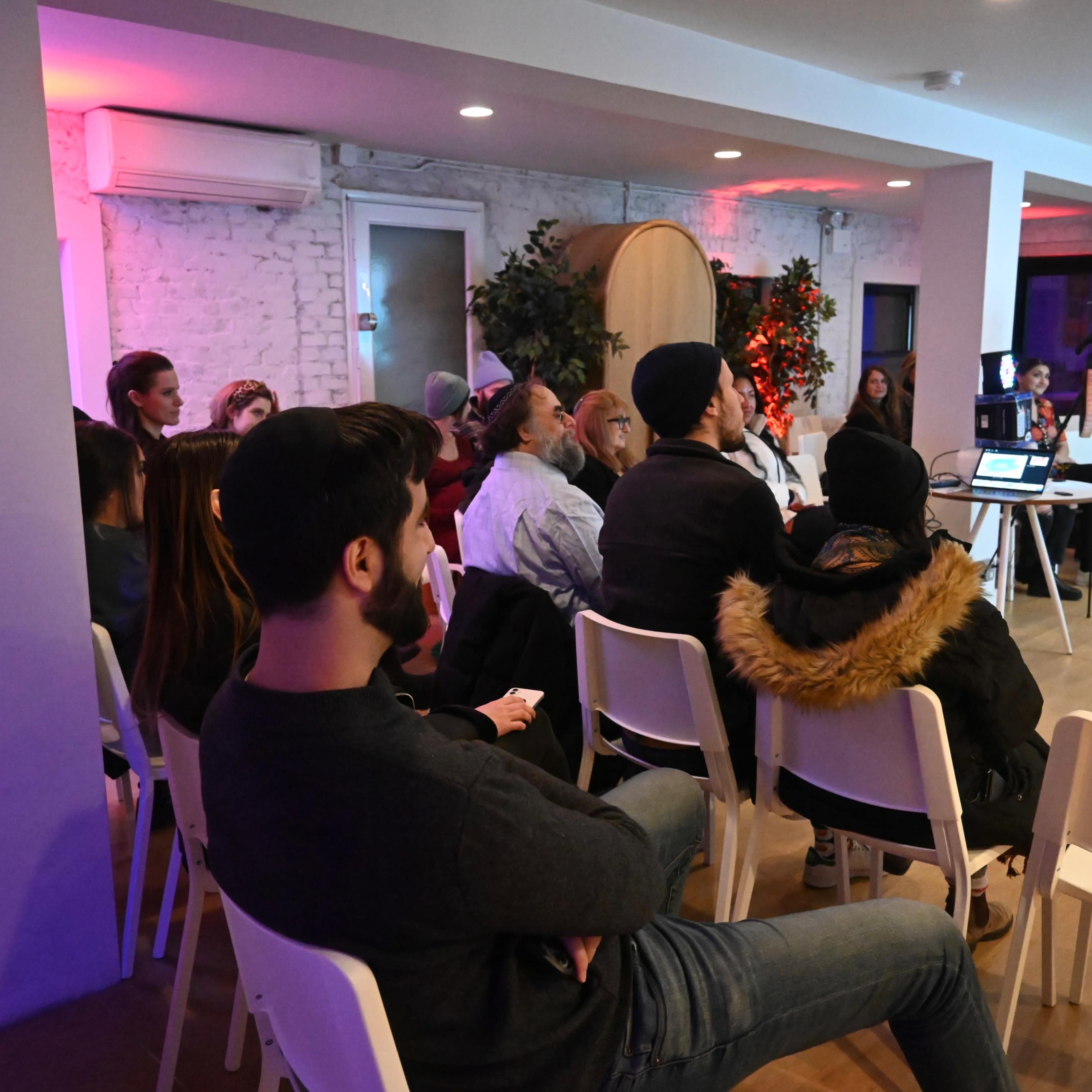 A group of people is seated in a meeting room with a projector displaying a presentation.