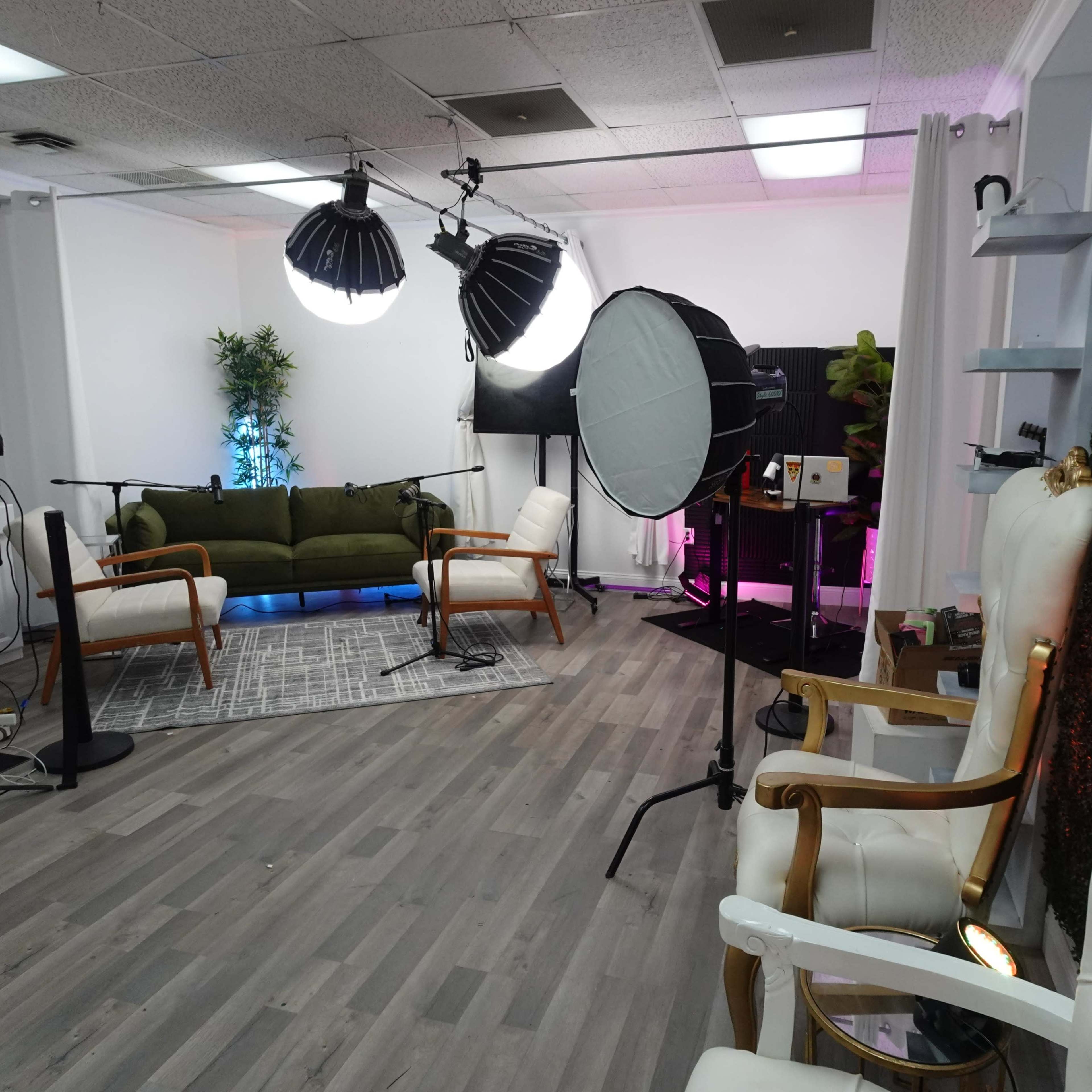 A modern studio setup with green sofas, microphones, and lighting equipment arranged for a recording session.