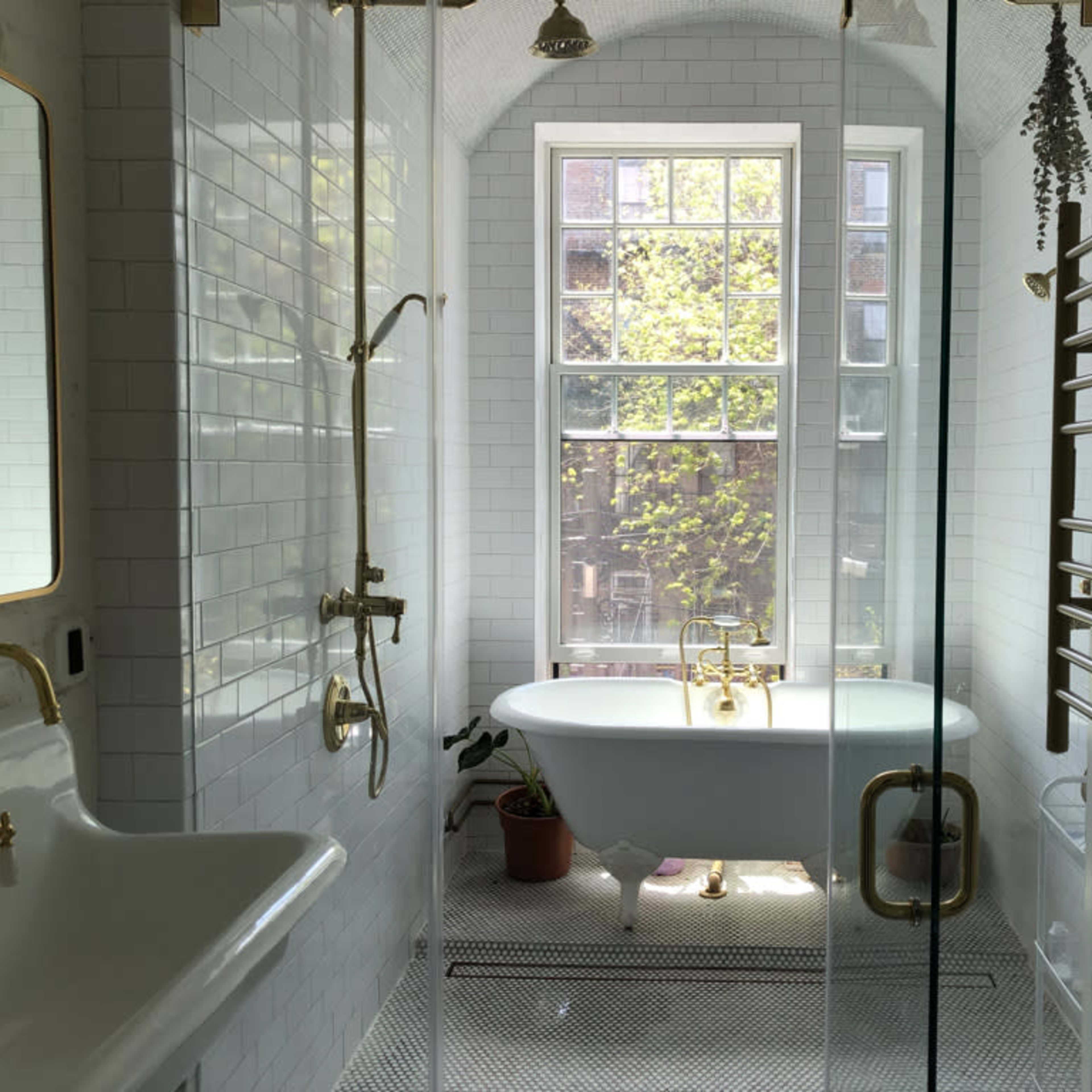 A modern bathroom featuring a freestanding tub, a spacious walk-in shower, and a large window allowing natural light to illuminate the space.