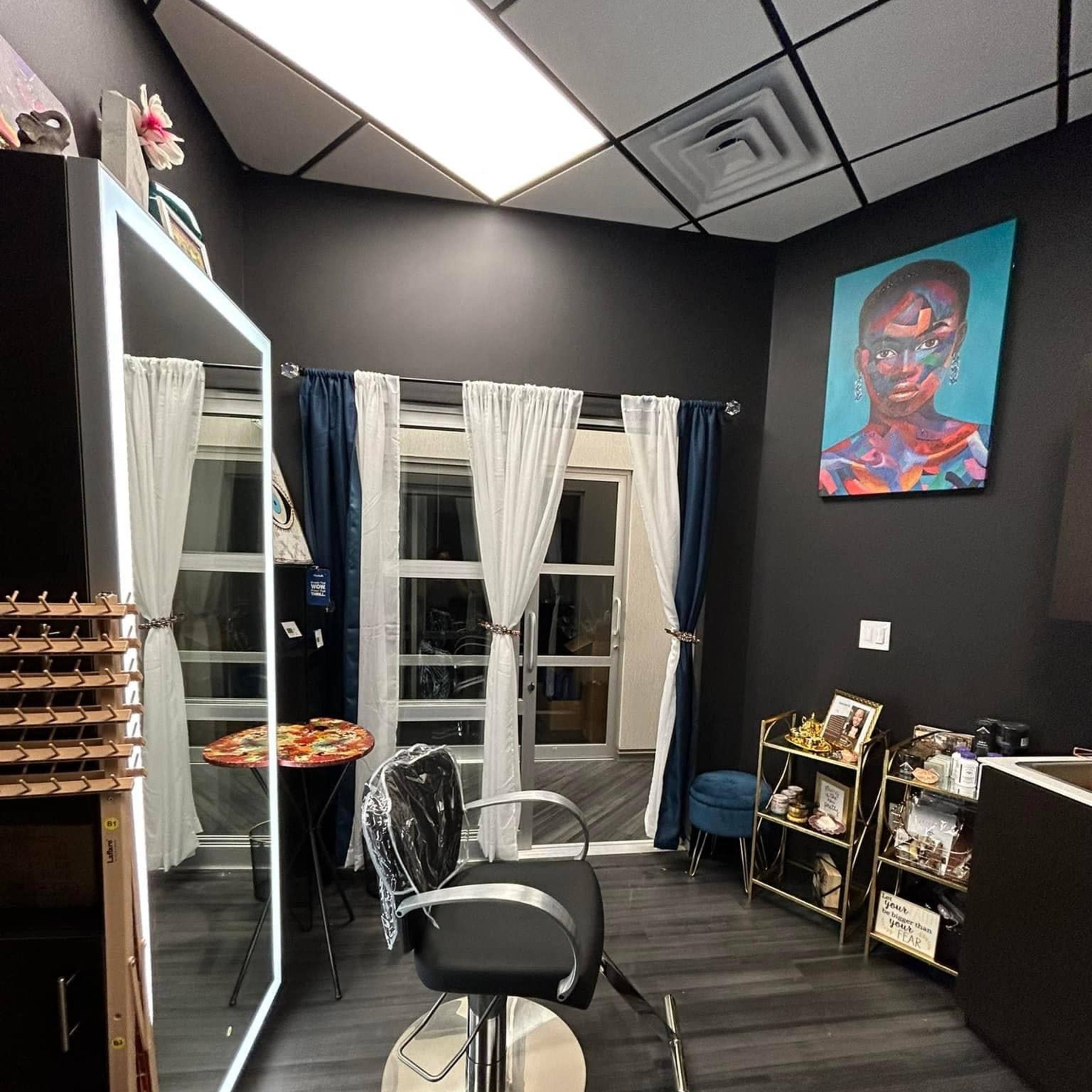 A small, modern salon interior with a styling chair, a large mirror, and artwork on the walls.