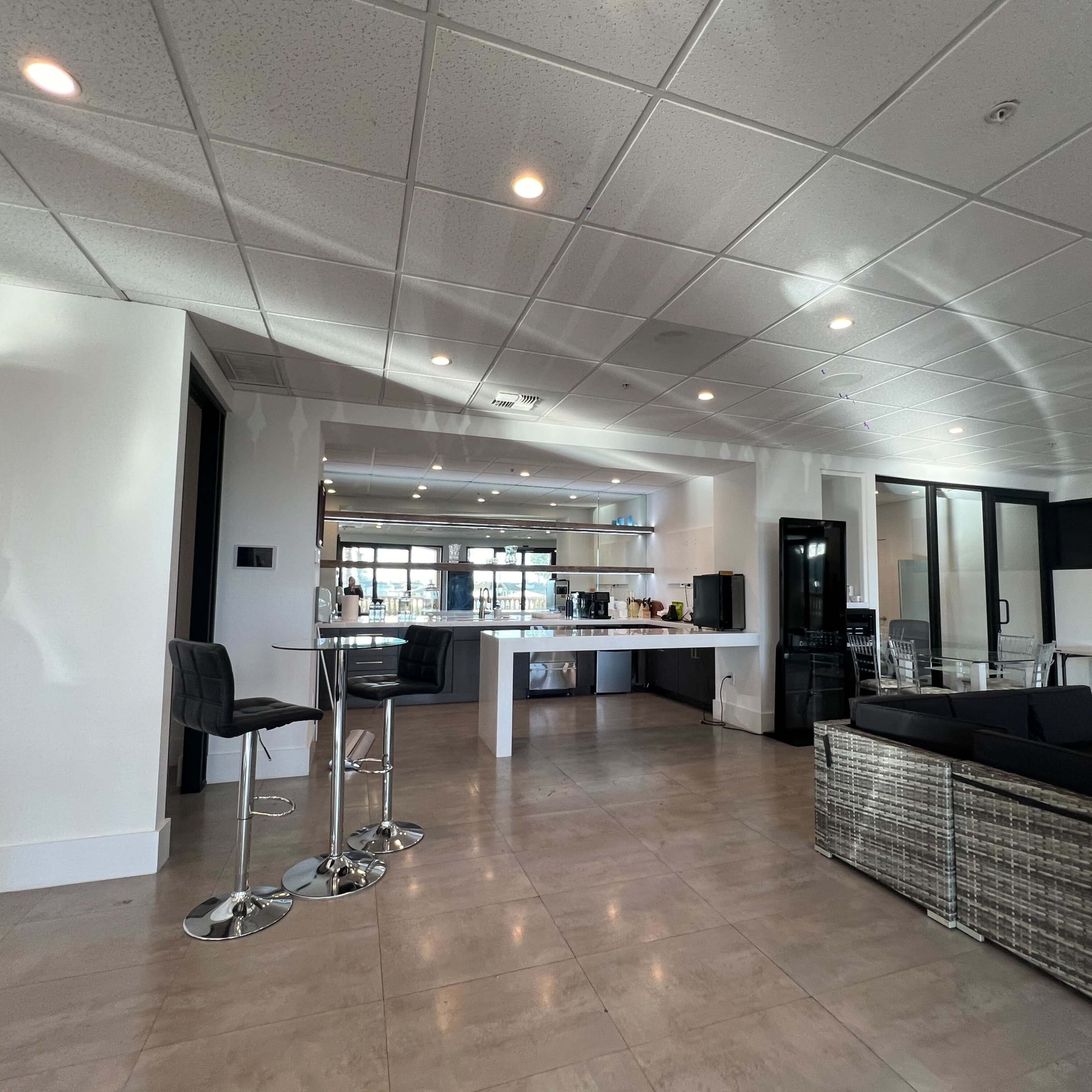 A modern interior space featuring a bar area with high stools, a polished countertop, and a lounge seating arrangement.