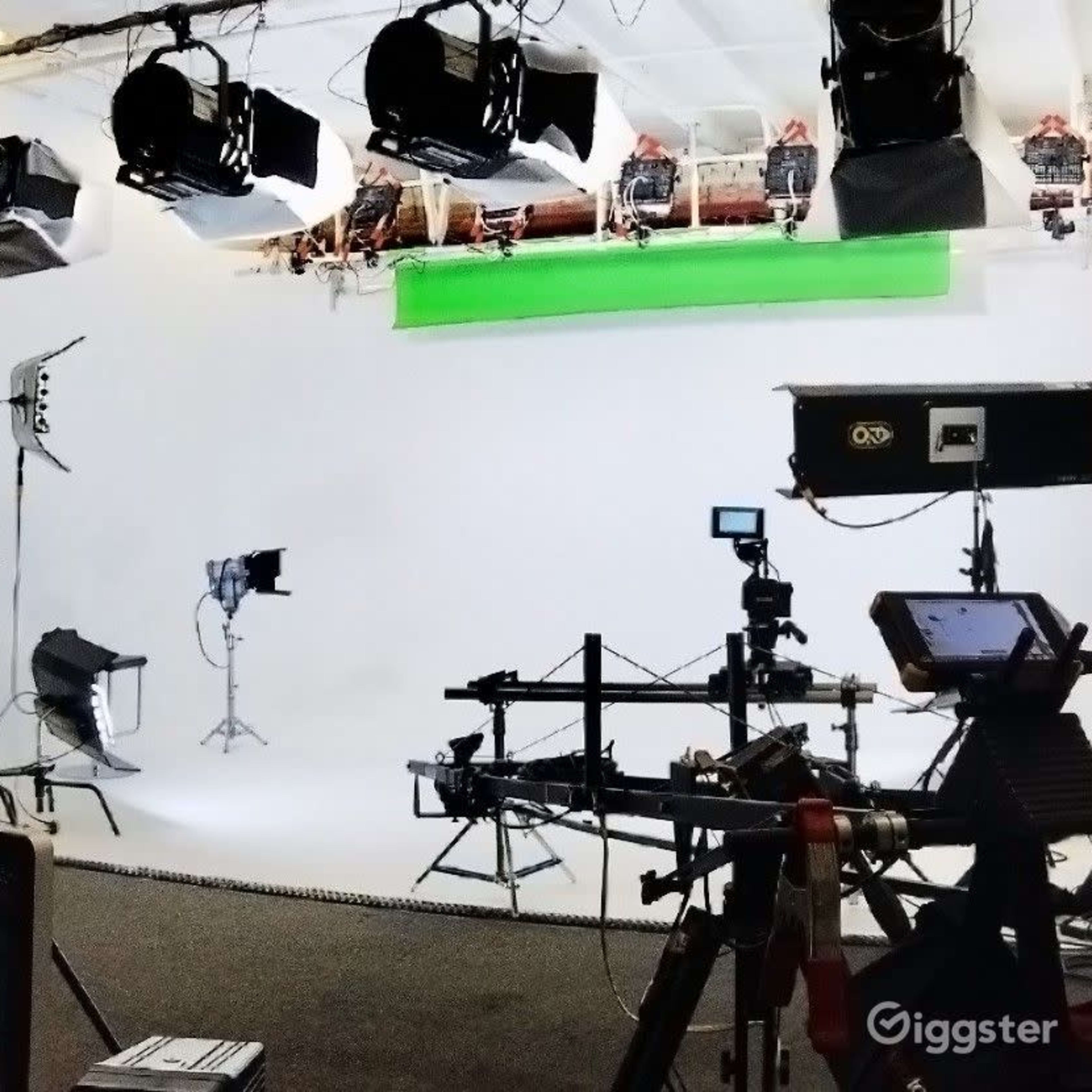 A film studio setup with multiple cameras, lighting equipment, and a blank backdrop.