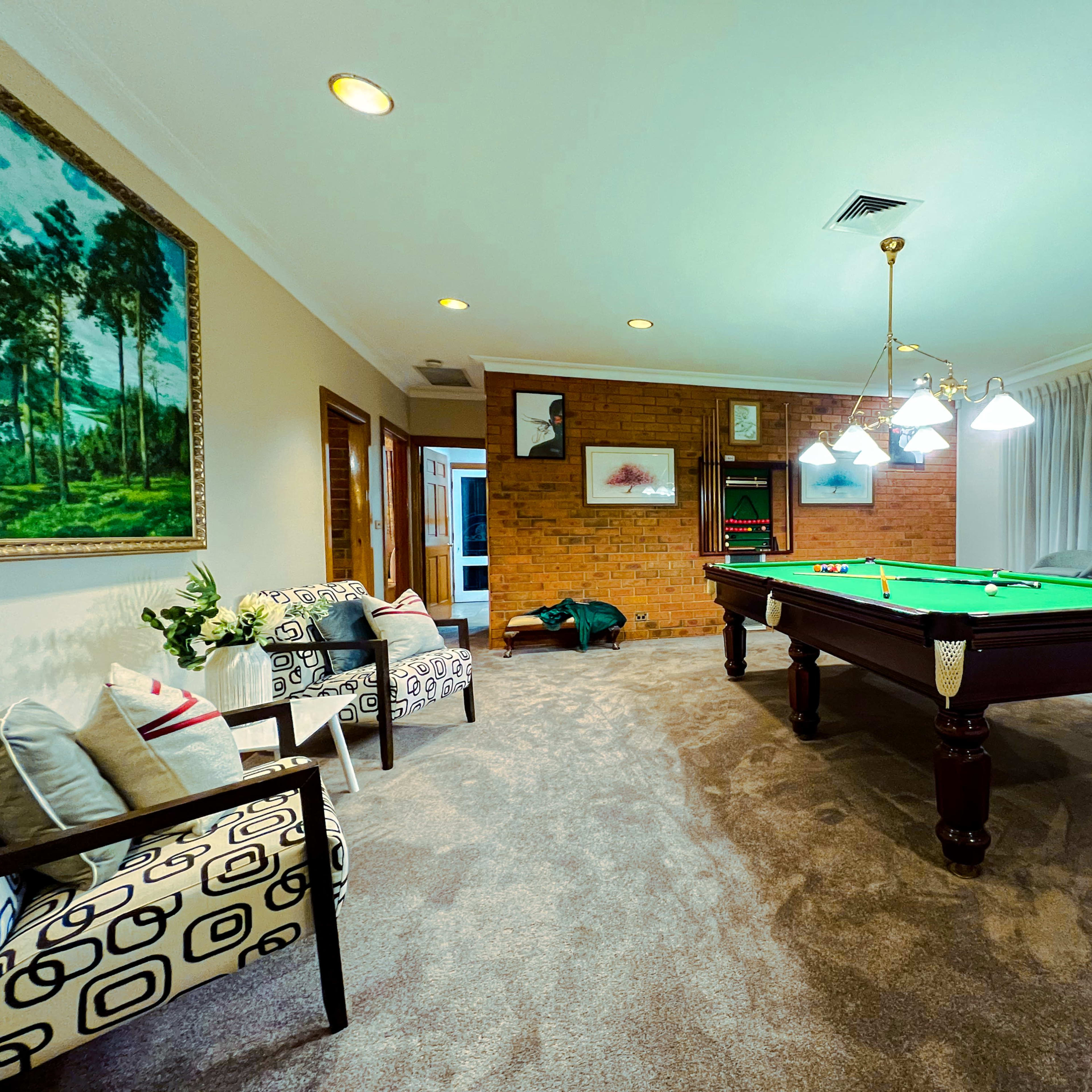 The room features a billiard table at its center, surrounded by upholstered chairs and paintings on the walls.