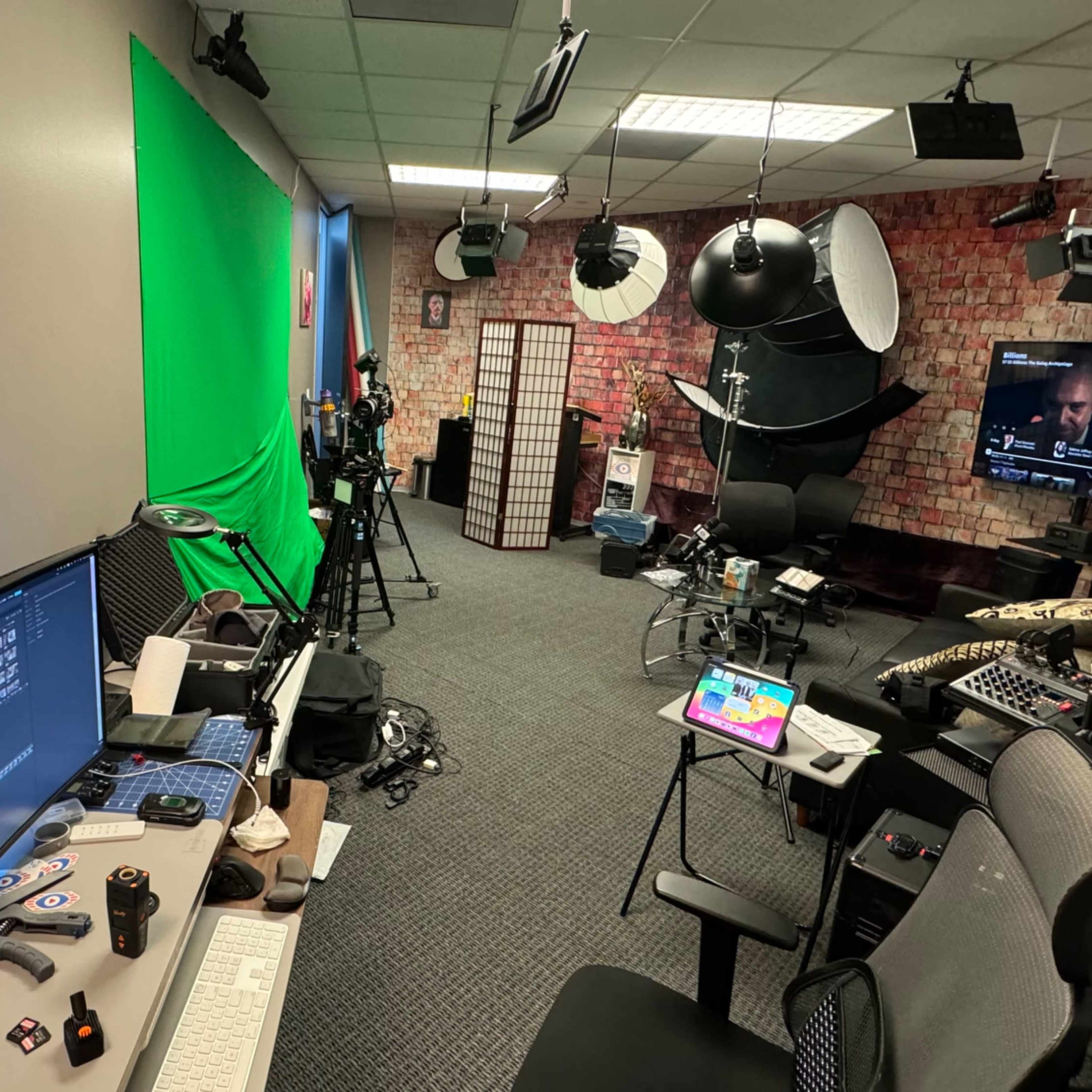 A recording studio equipped with a green screen, cameras, lighting equipment, and computer workstations.