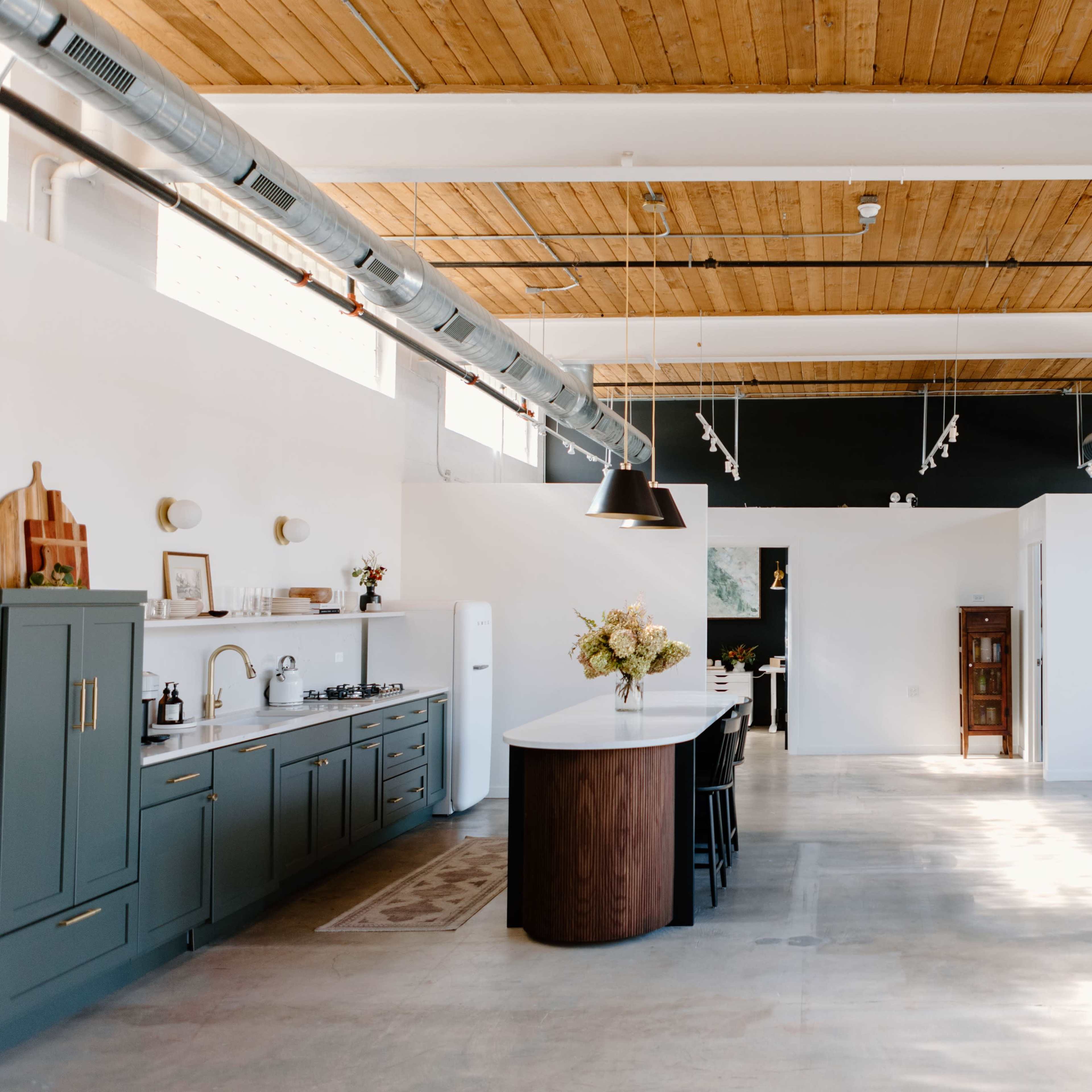 A spacious kitchen and dining area with a large island, modern cabinetry, and a minimalist design featuring large windows.