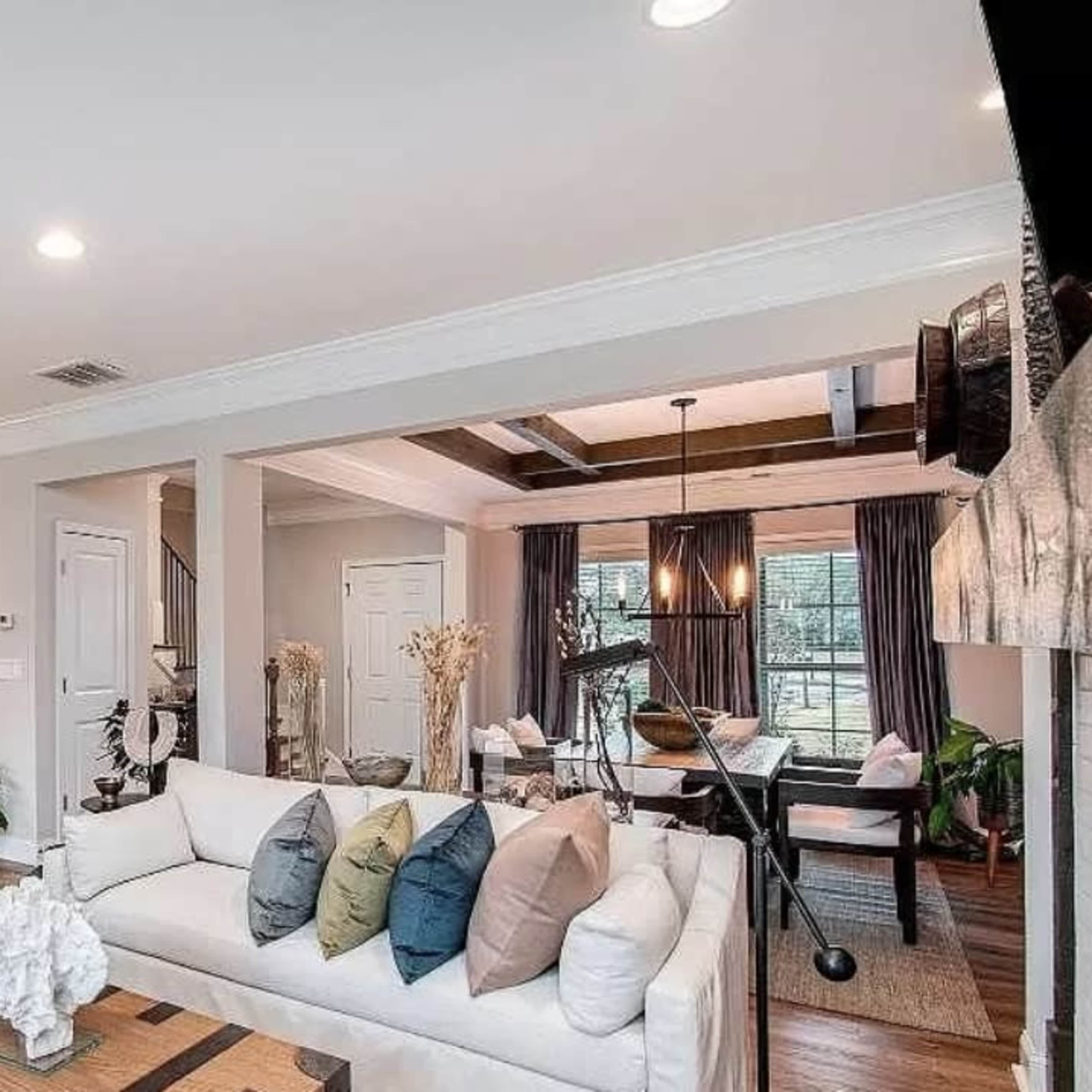 A modern open-concept living area that includes a kitchen, dining space, and a sitting area with a sofa and decorative pillows.