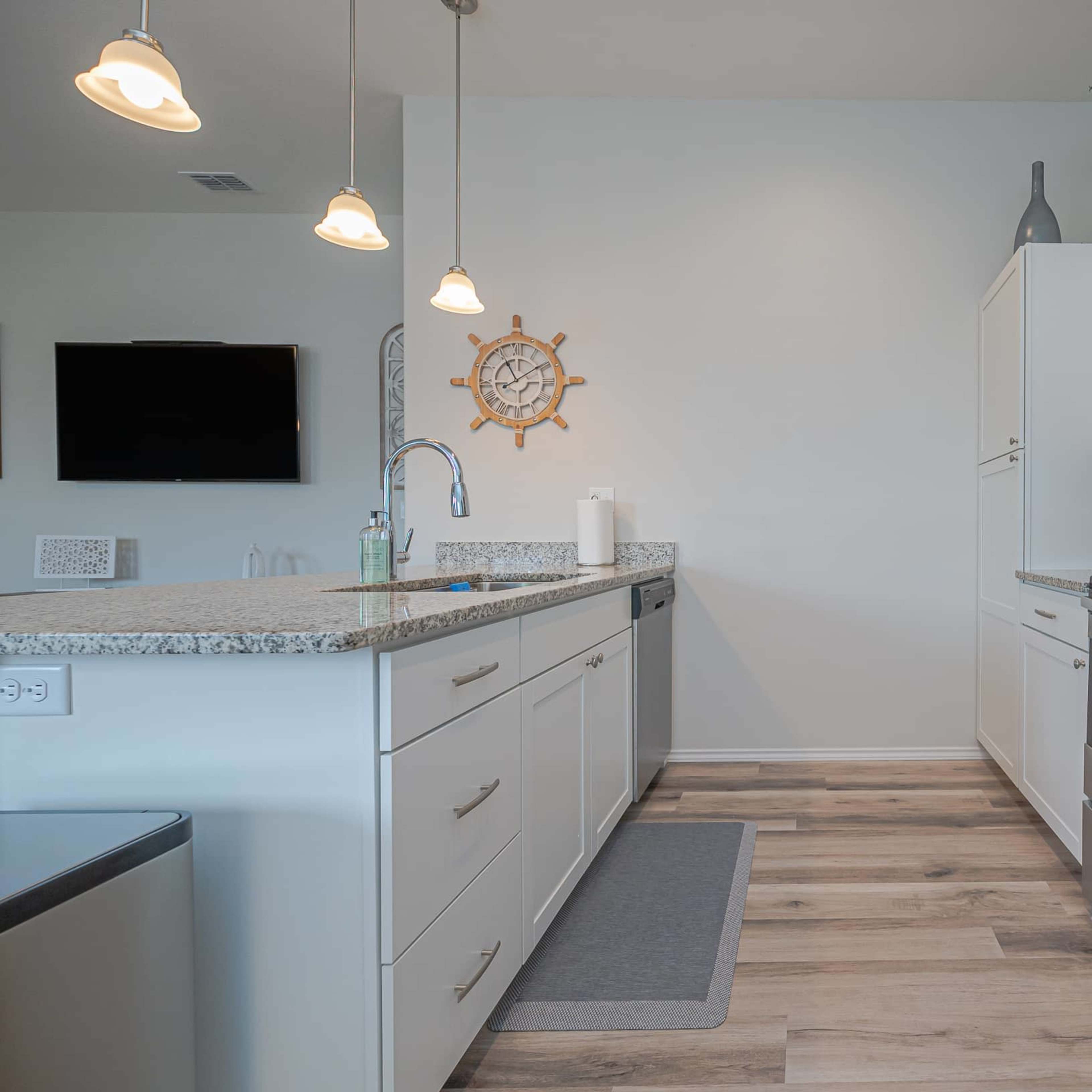 The kitchen features stainless steel appliances, a granite countertop, and white cabinetry in a modern layout.
