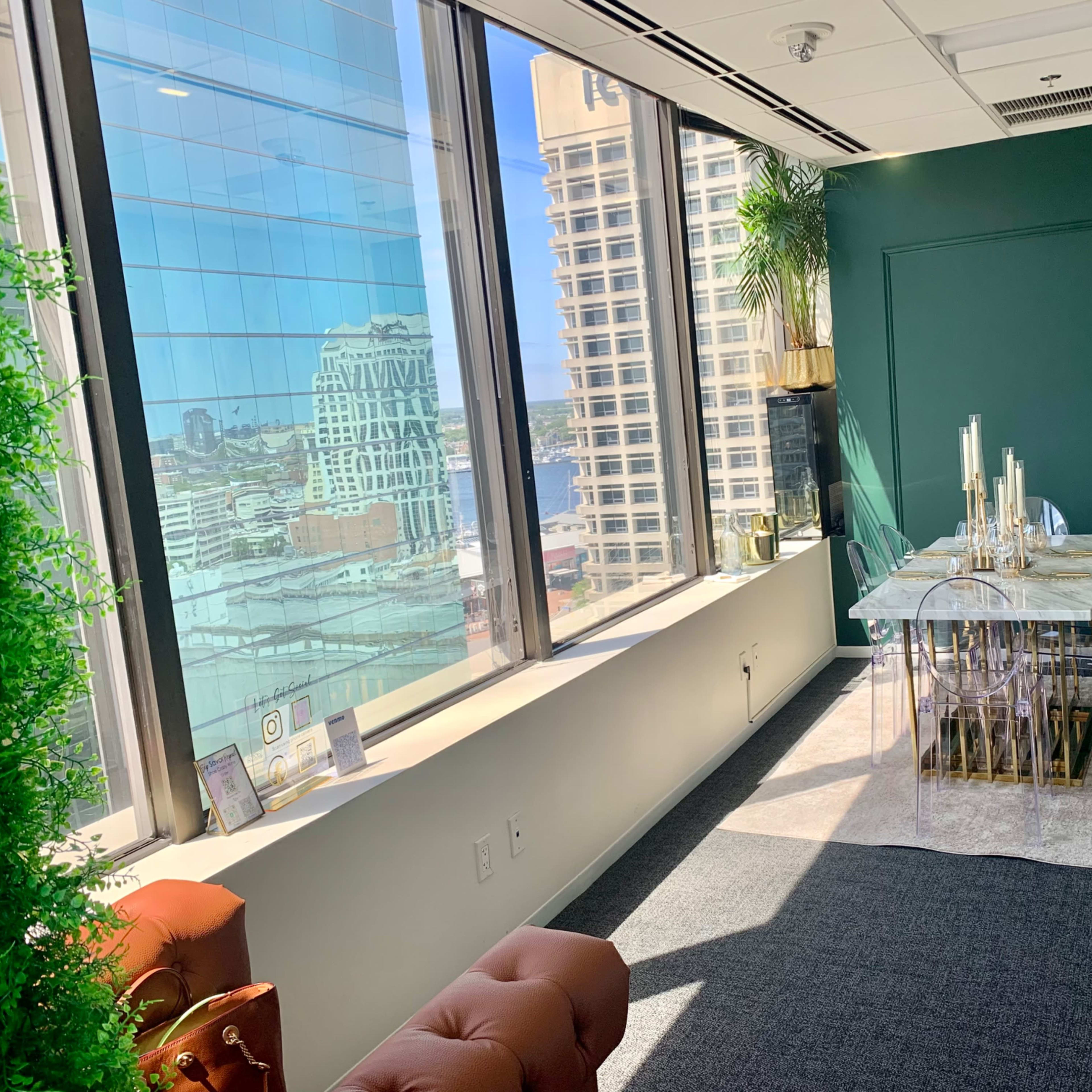 A modern conference room with a glass dining table and illuminated candles, surrounded by large windows offering a view of a cityscape.