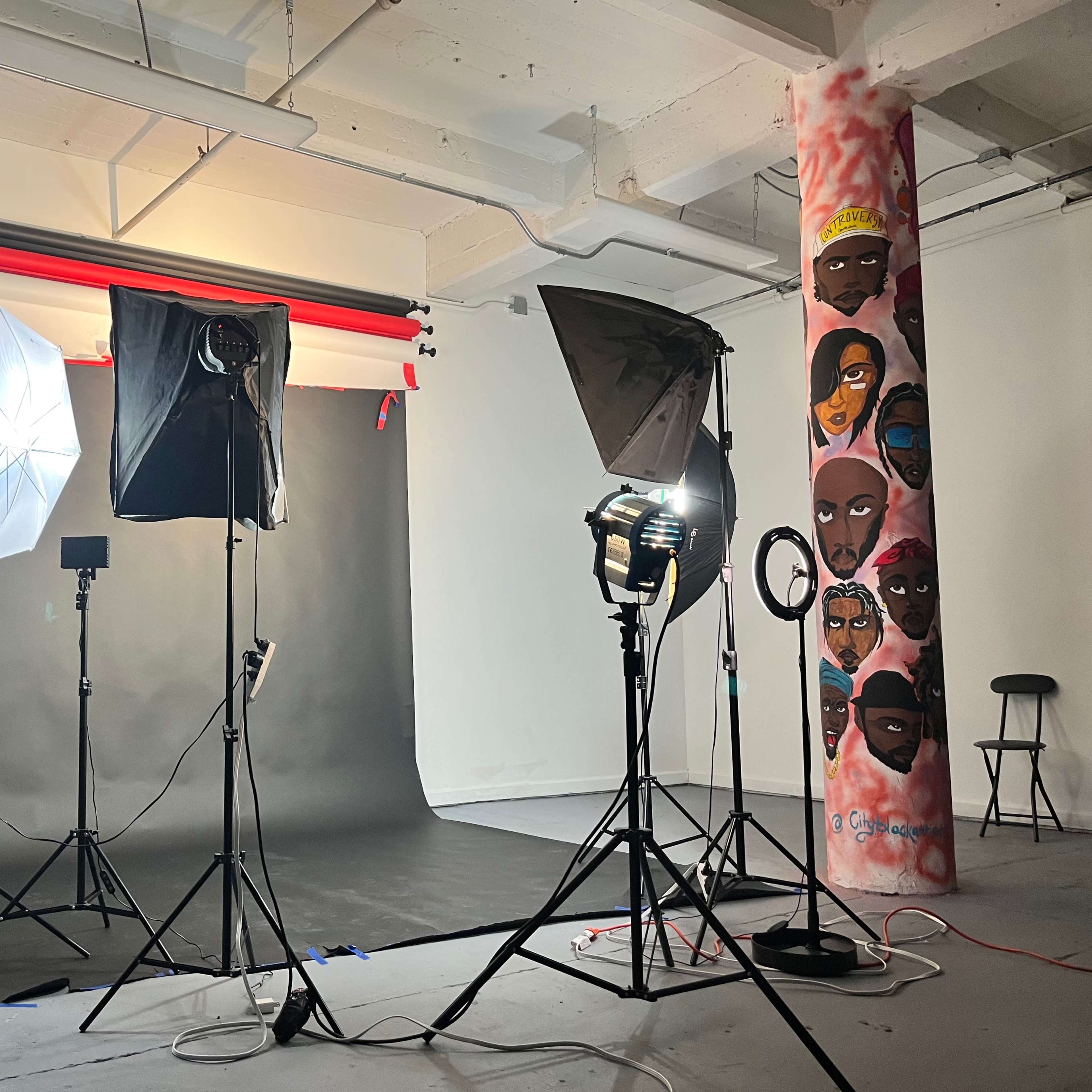 A photography studio set up with multiple lights, backdrops, and painted columns.