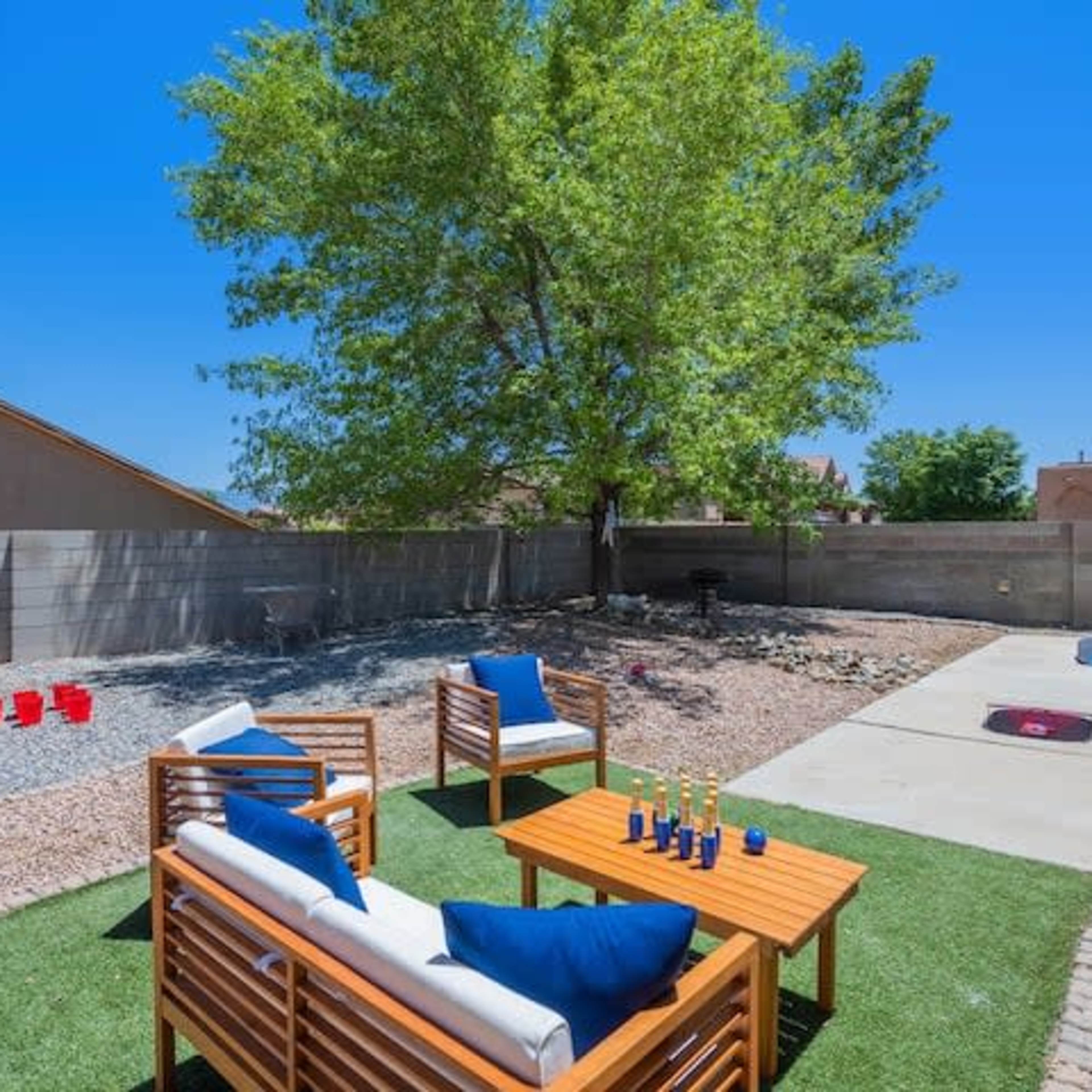 A backyard with two wooden seating areas, a large tree, and a gravel-covered section.