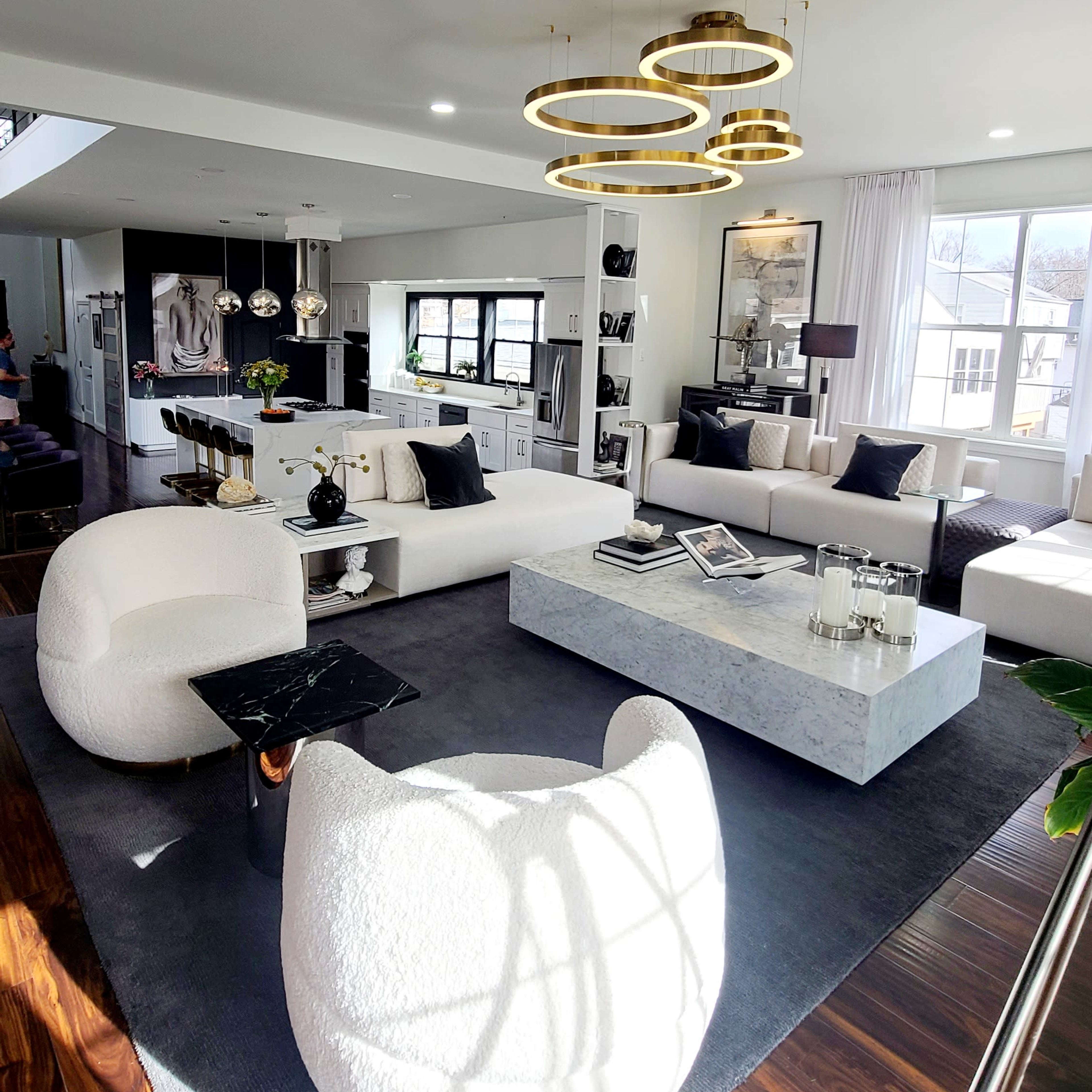 The living room features a modern design with white furniture, a rectangular marble coffee table, and a spiral chandelier.