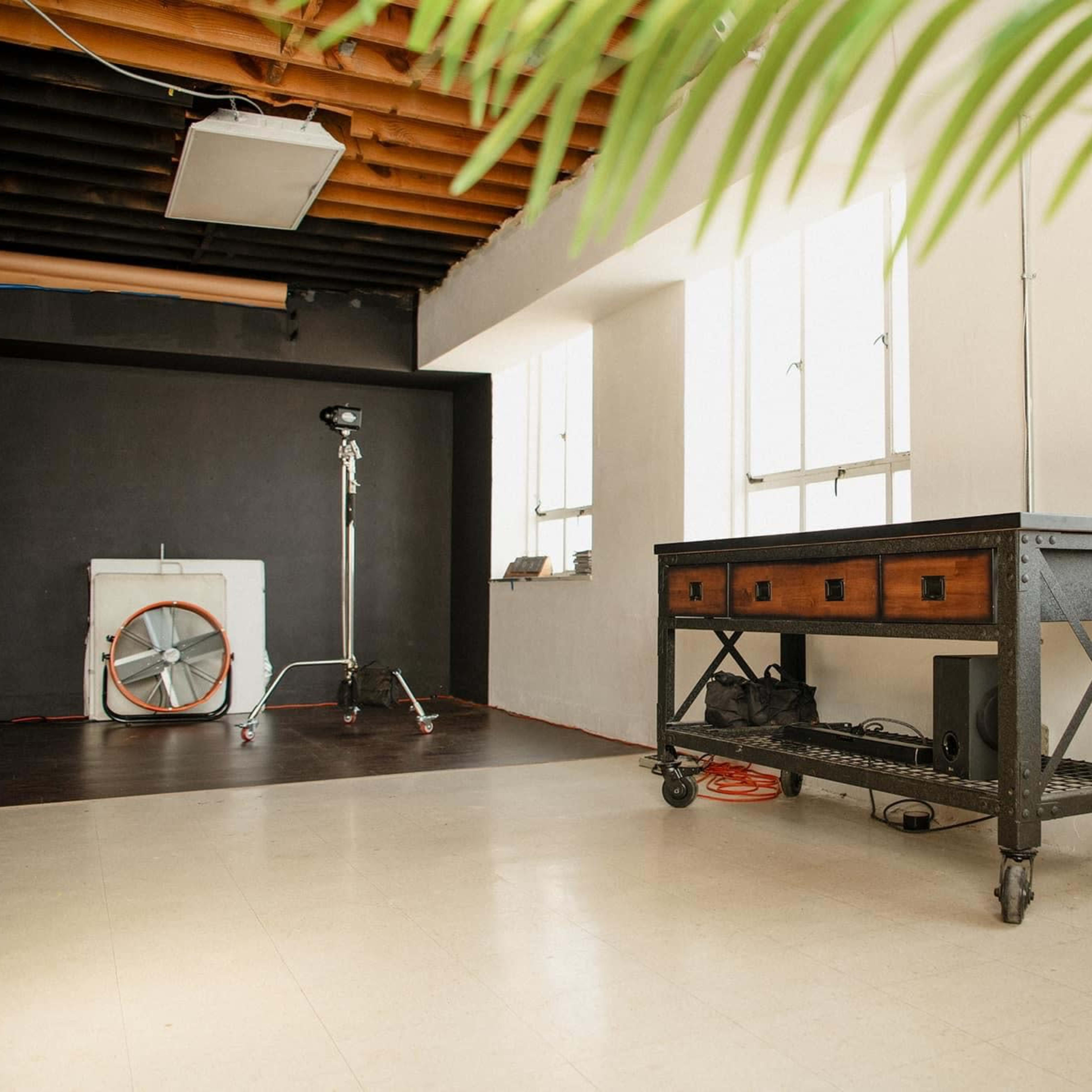 A spacious studio with a metal table on wheels, large windows, and a backdrop setup in the corner.