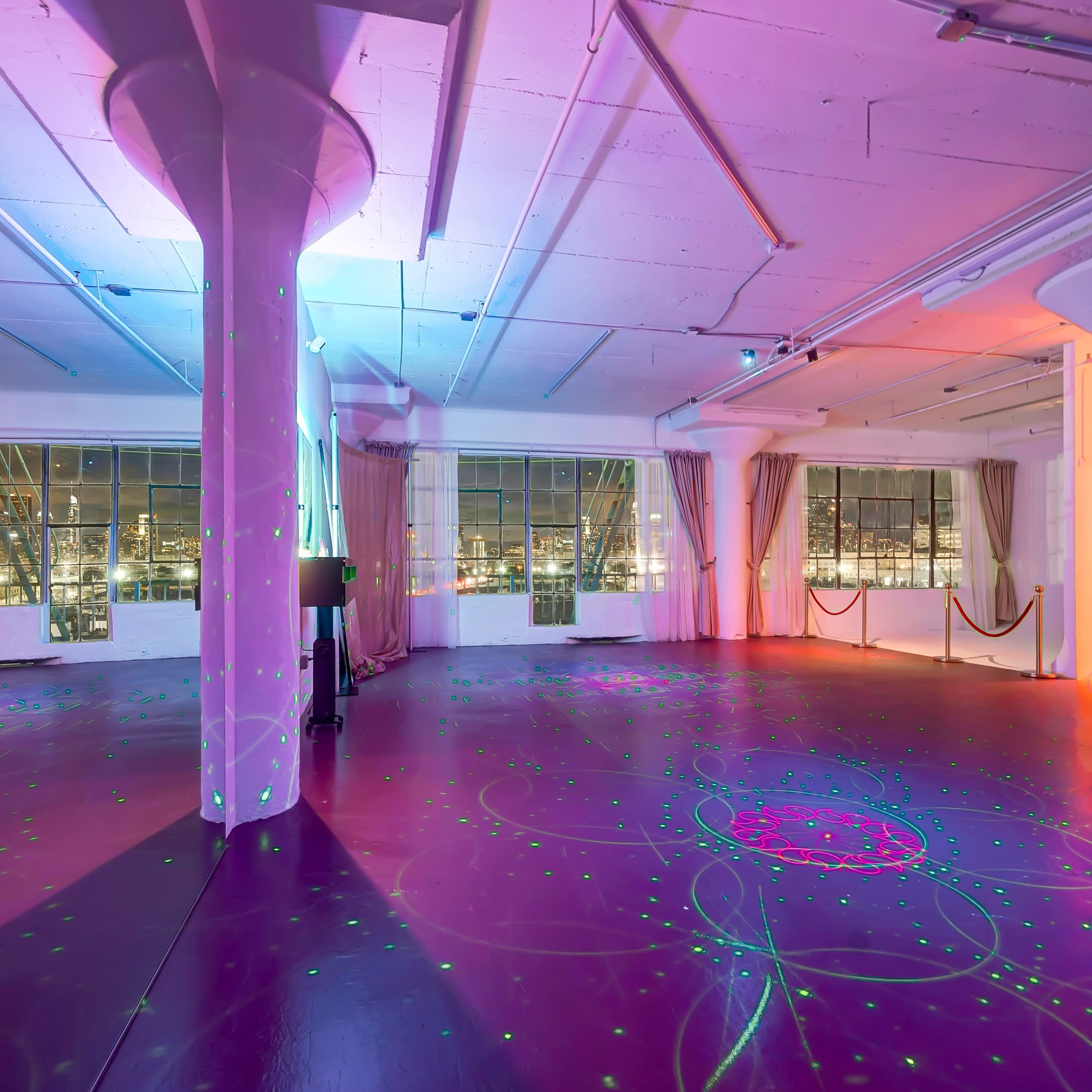 A spacious, well-lit room with illuminated columns and colorful light patterns projected onto the floor.