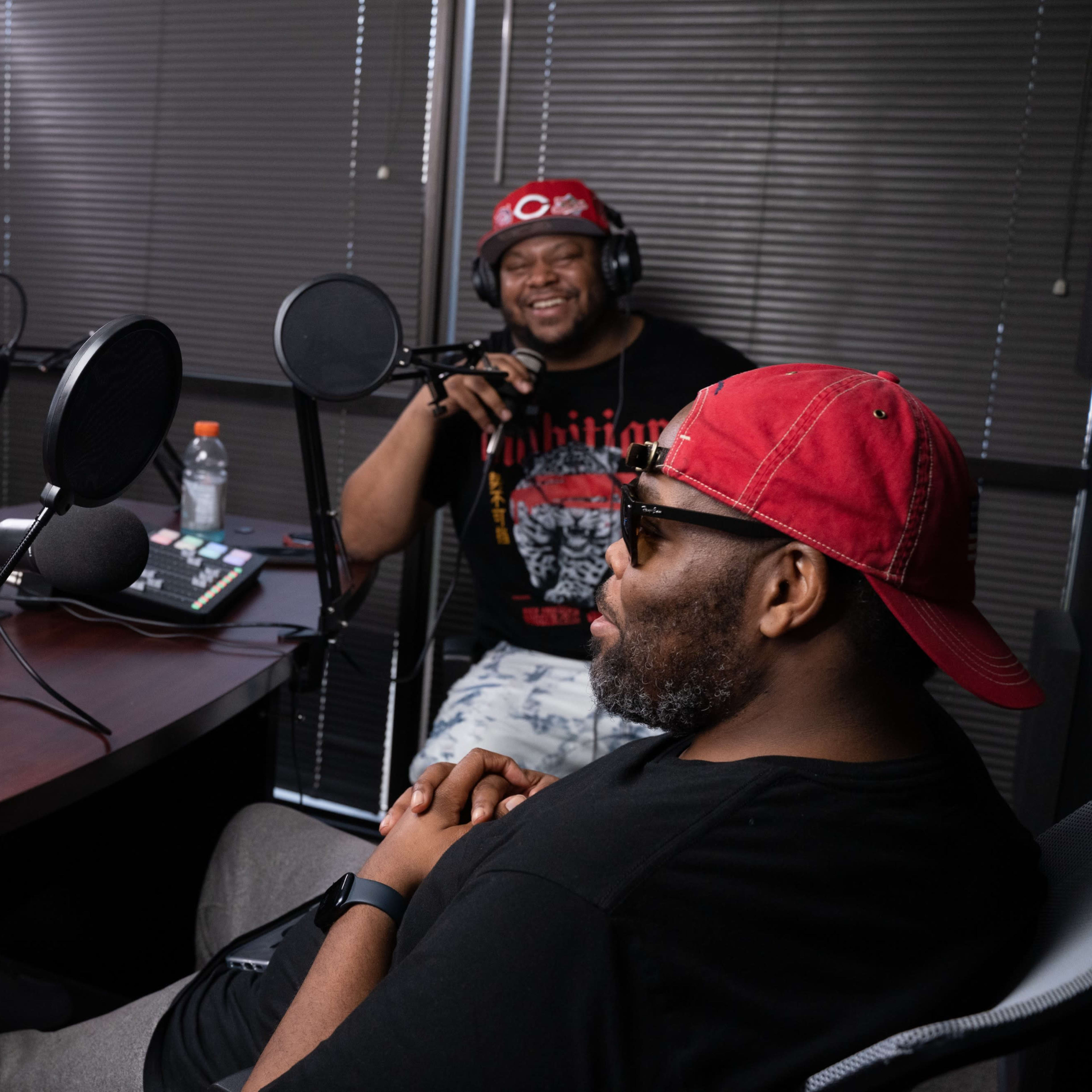Three men are engaged in a podcast discussion at a table with microphones and recording equipment.