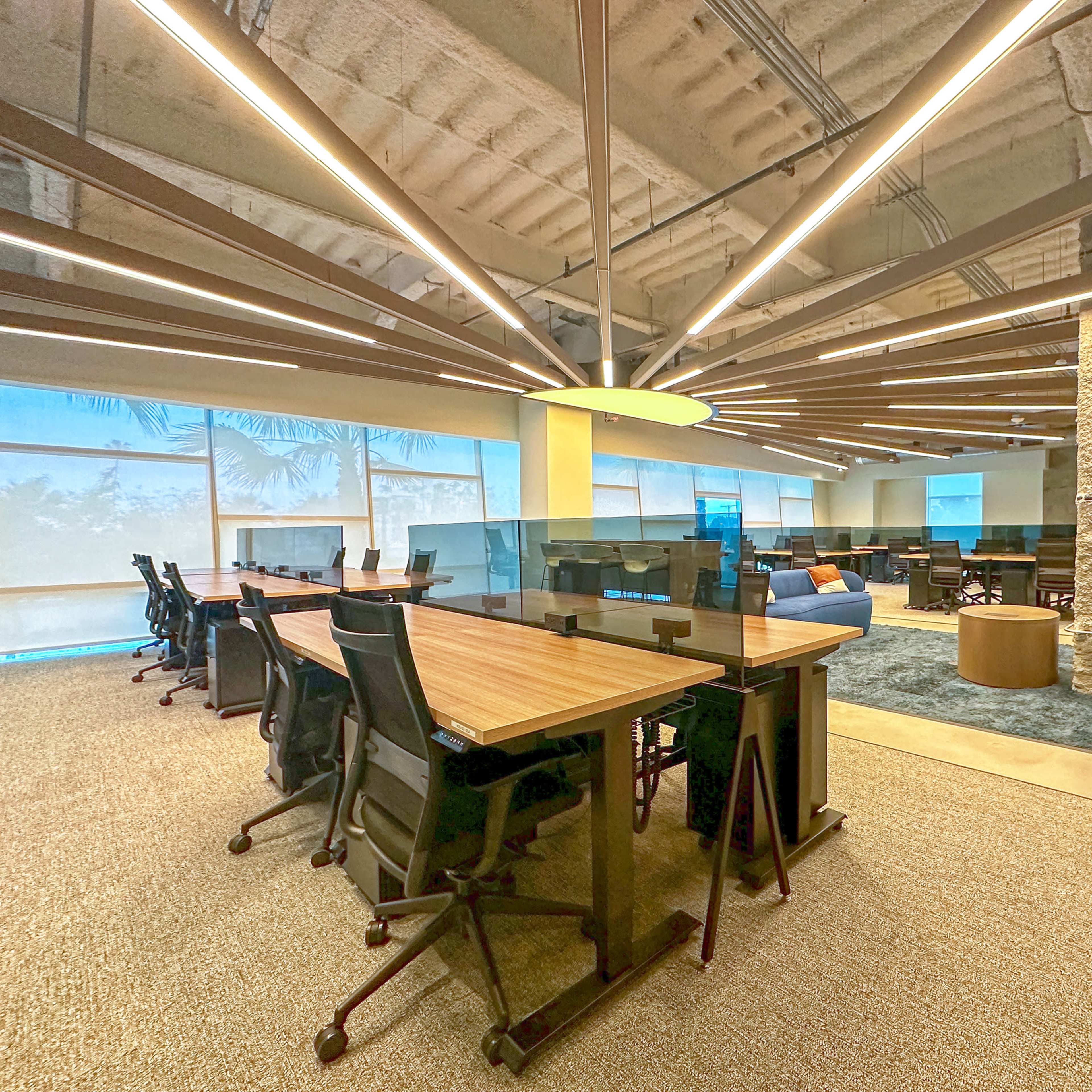 A modern office space with a long conference table, ergonomic chairs, and large windows allowing natural light to enter.