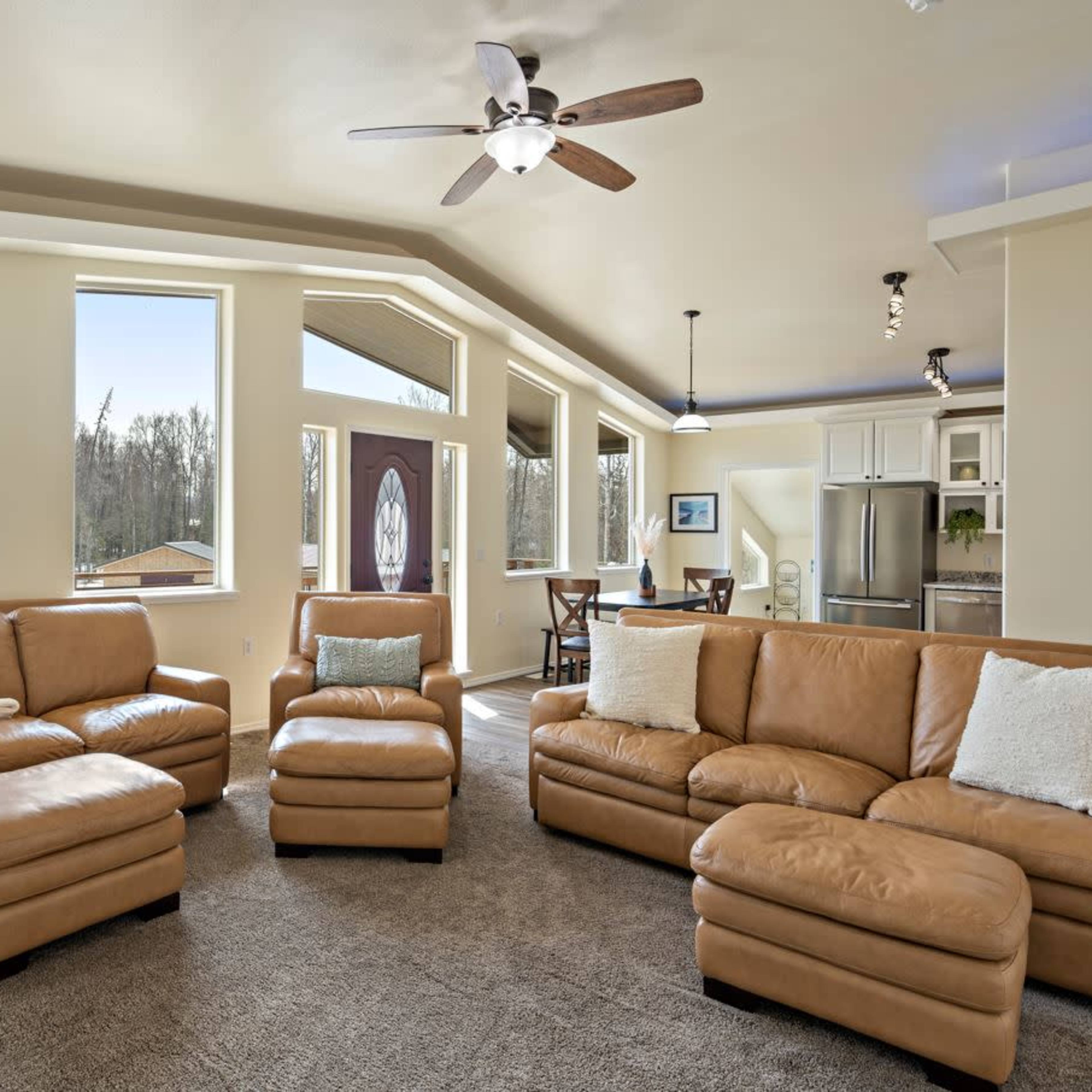 A spacious living room with leather furniture, large windows, and an adjoining dining area visible in the background.