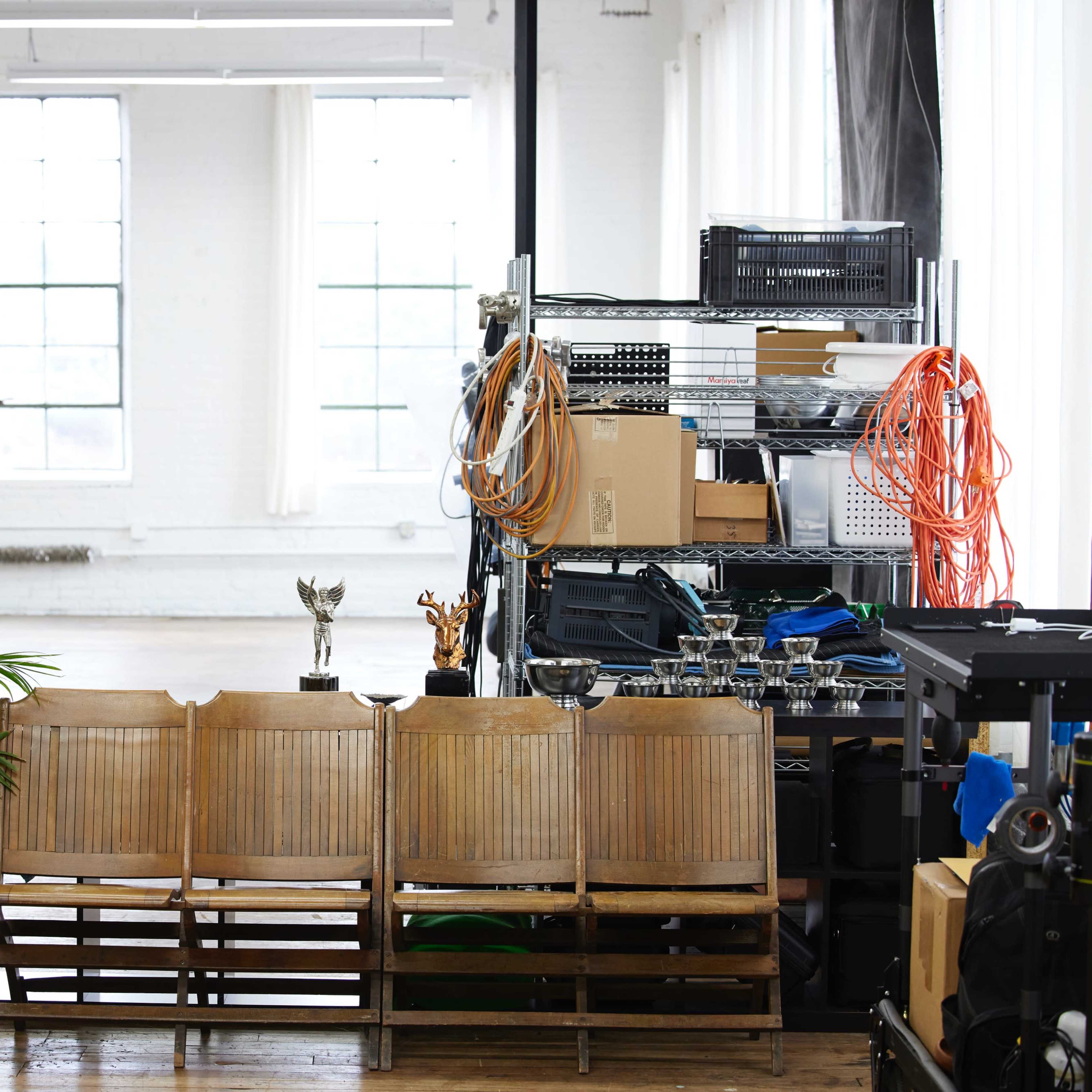 A bright, open interior space with wooden chairs lined up in front of a shelf filled with various items, including trophies and equipment.