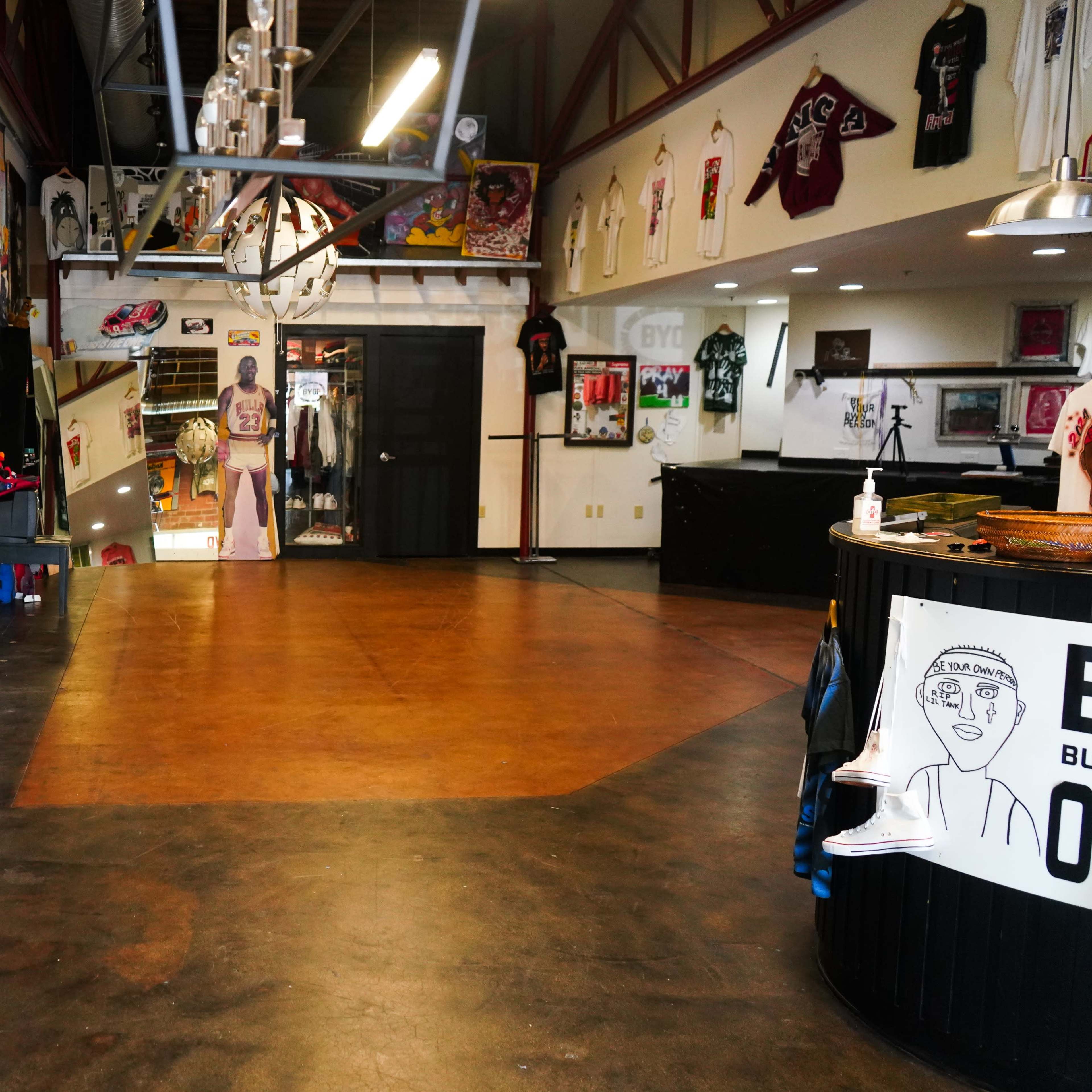 An indoor space featuring a polished floor, various murals and artwork on the walls, and merchandise display areas.
