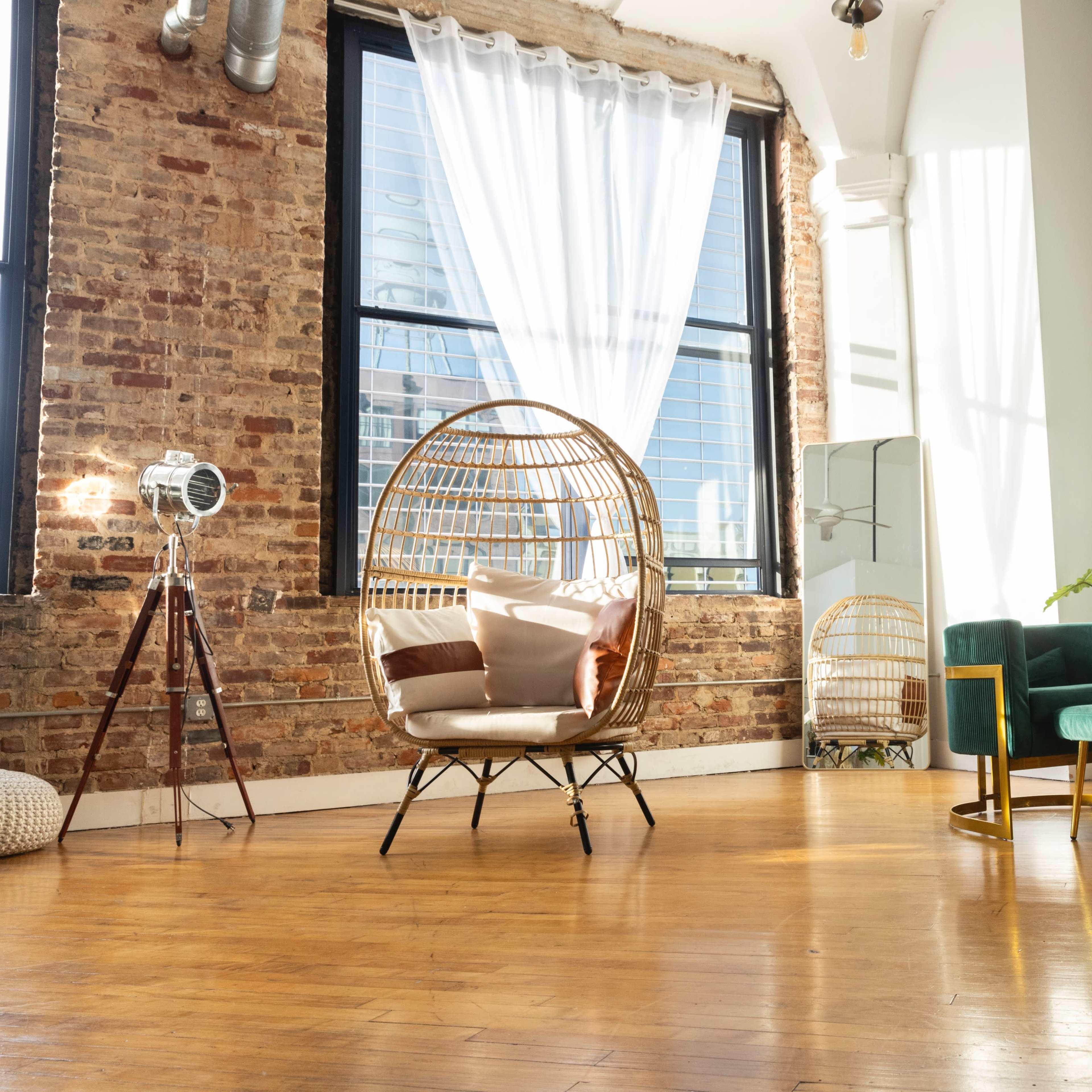 A well-lit room features a cozy seating area with a teal sofa, a round coffee table, a decorative chair, and large windows showcasing a view of the city.