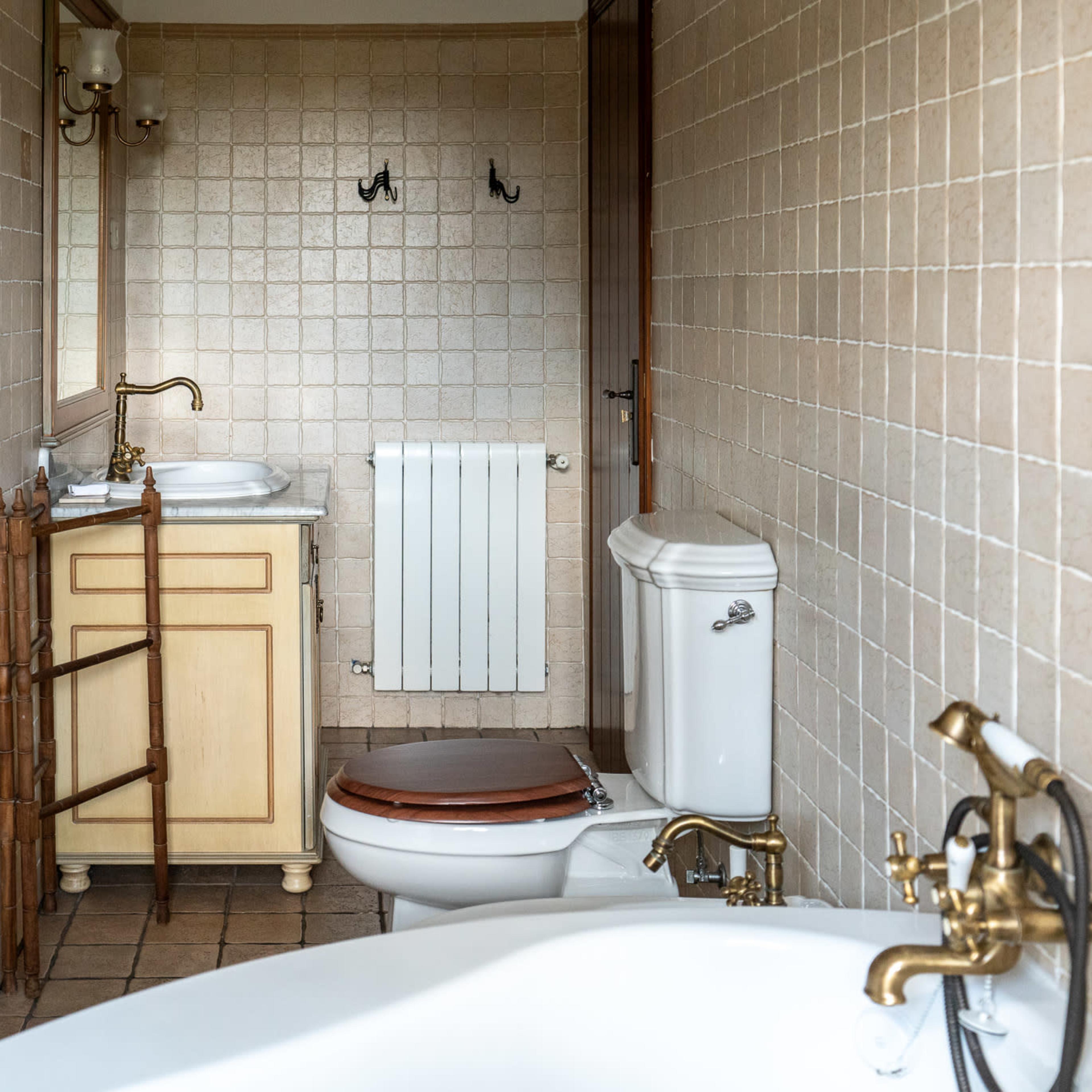 A bathroom with a sink, toilet, and bathtub, featuring tiled walls and a wooden cabinet.