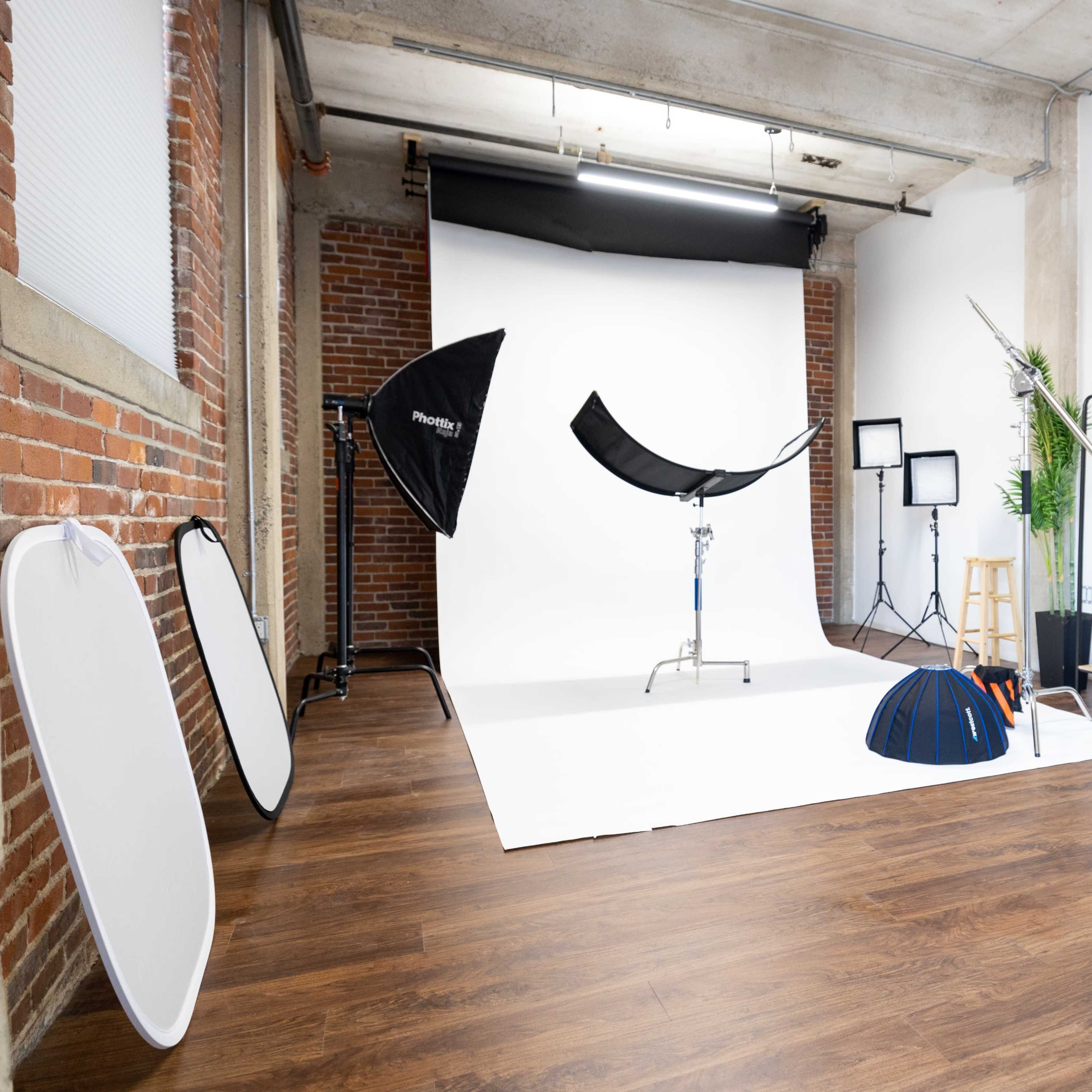 A photography studio setup with various equipment including backdrops, light stands, reflectors, and a mirror.