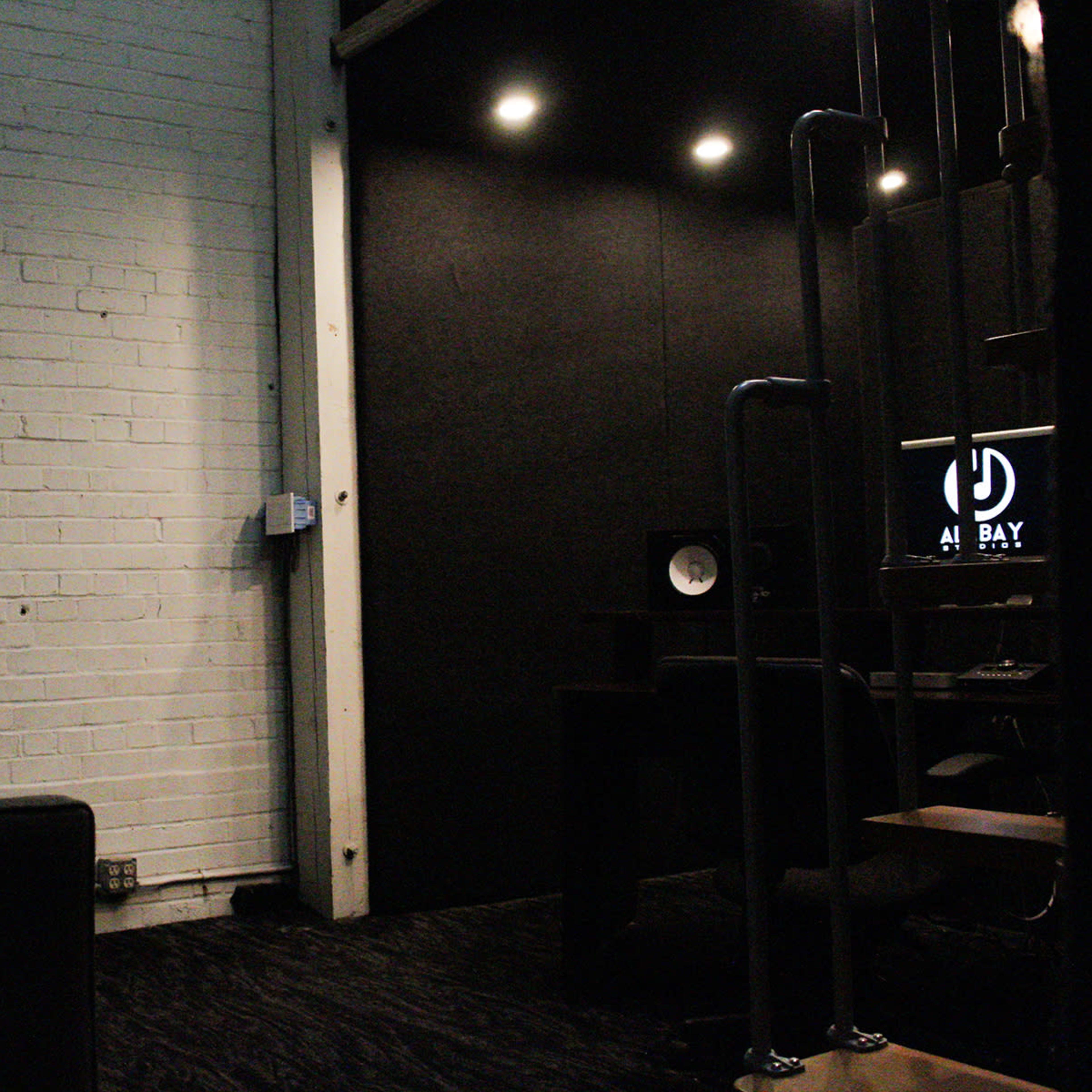 A minimalistic room with a white brick wall, a dark fabric wall, and a computer setup in a corner.