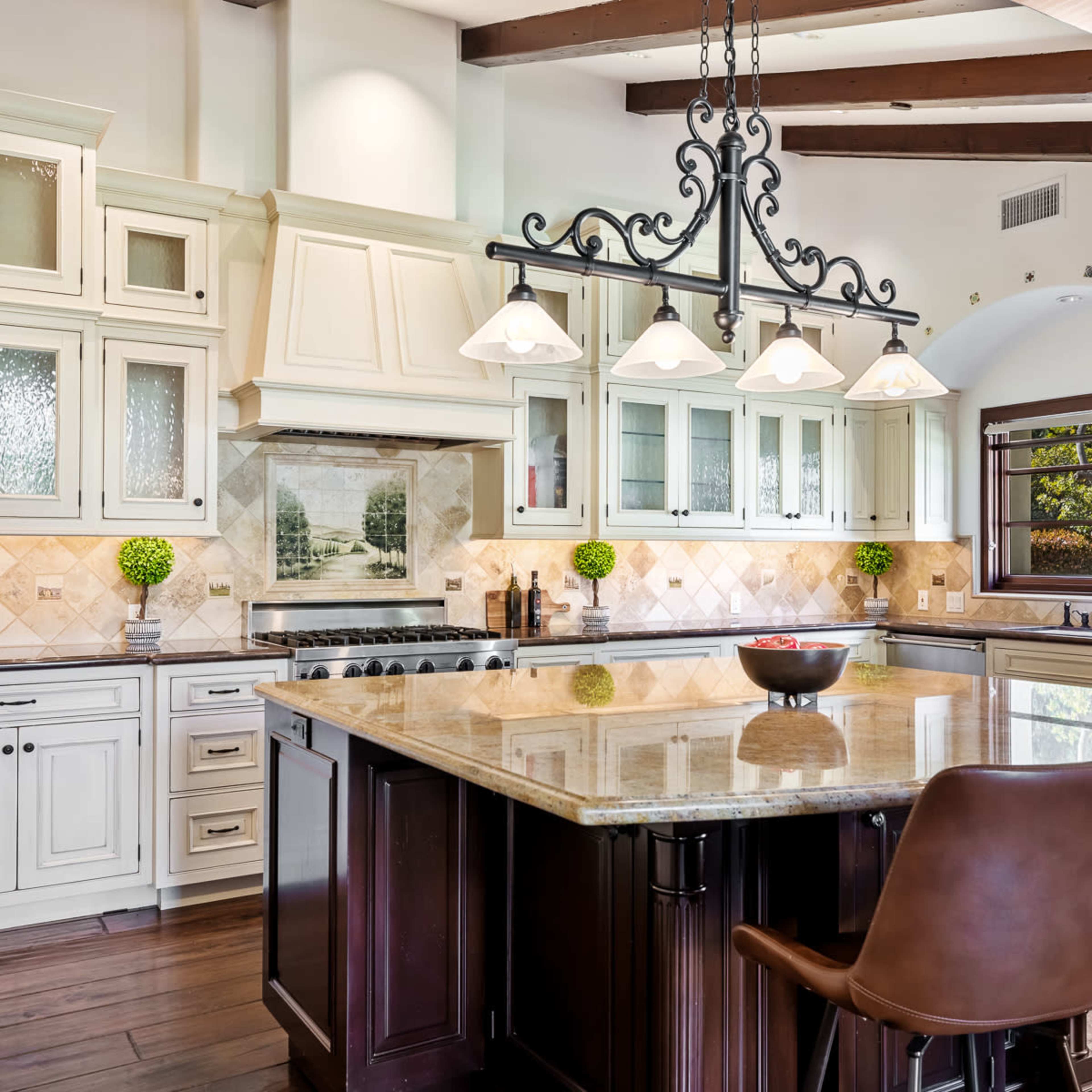 A spacious kitchen featuring white cabinets, a large granite island, and hanging pendant lights over the eating area.