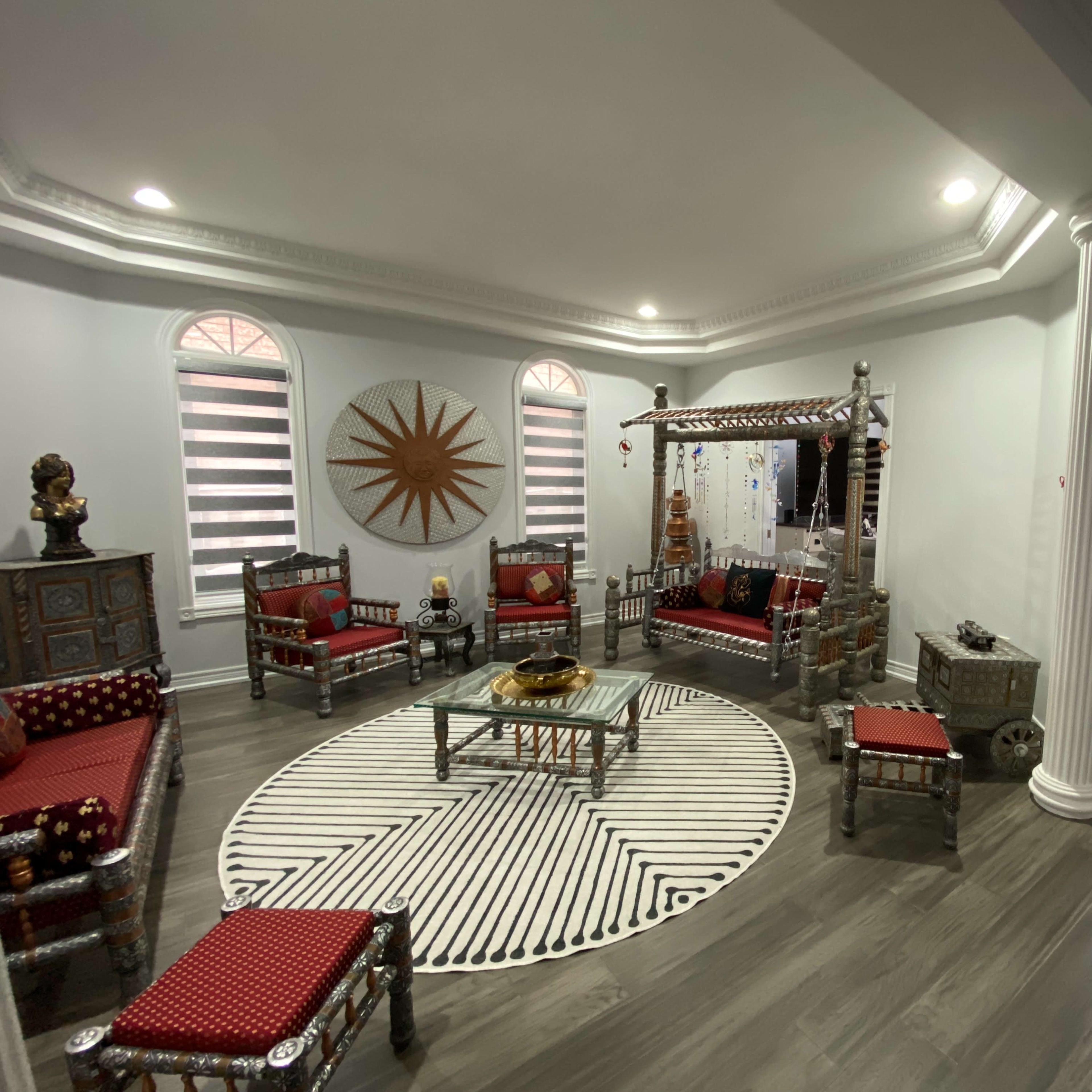 The room features a decorated seating area with silver-framed furniture arranged around a circular rug and a coffee table.