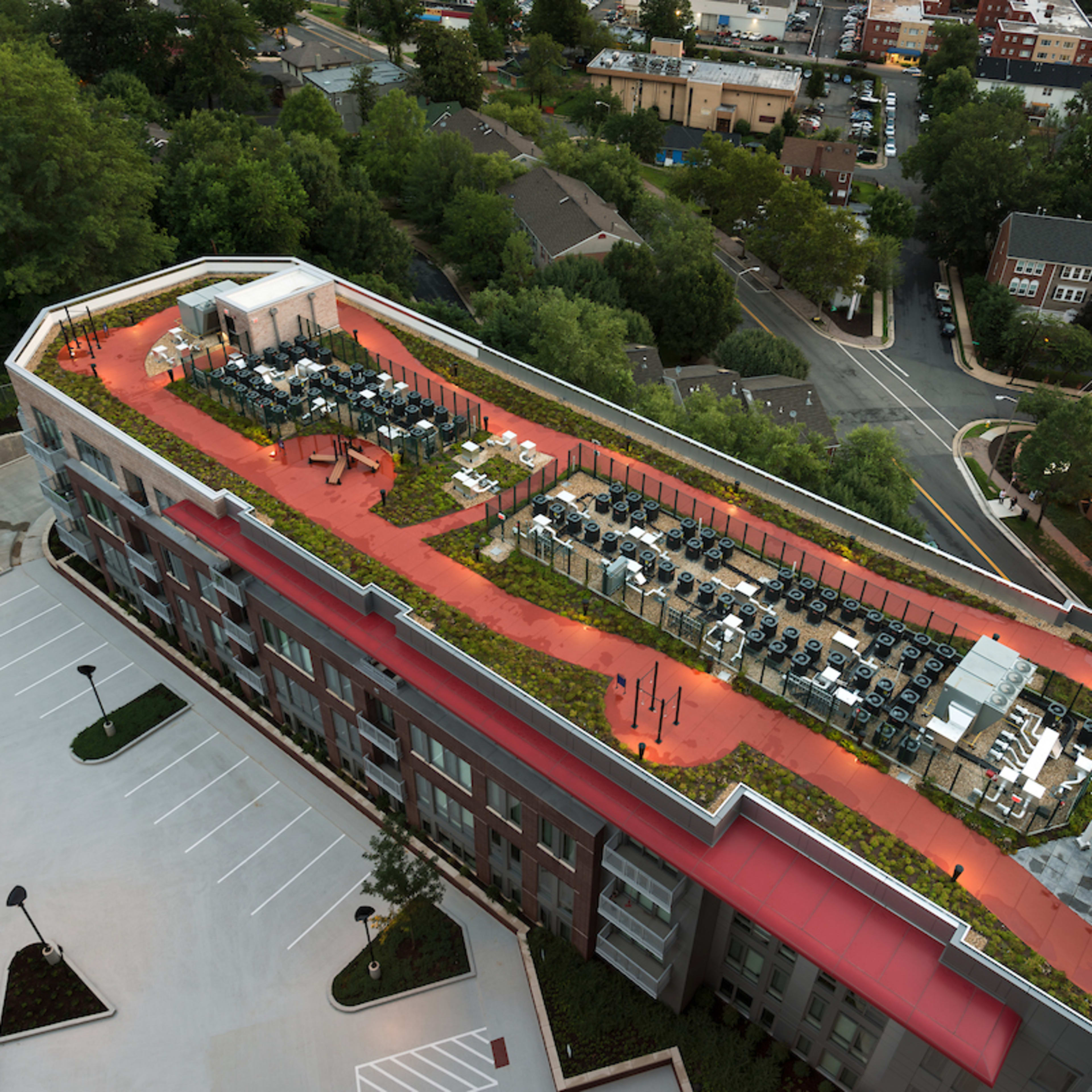 An aerial view of a modern building with a landscaped rooftop terrace featuring seating areas and greenery.