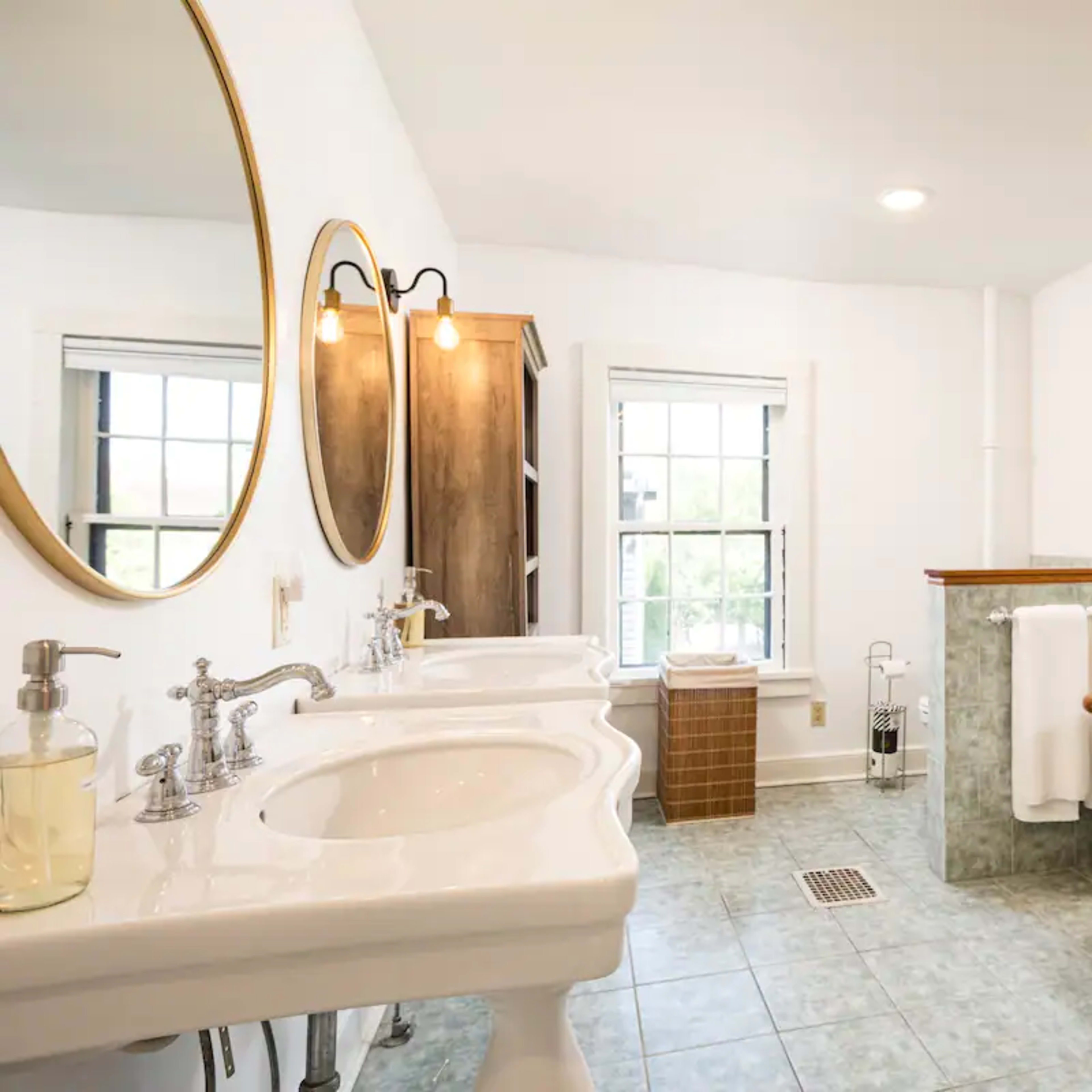 A spacious bathroom features two sinks, a freestanding bathtub, and large windows providing natural light.