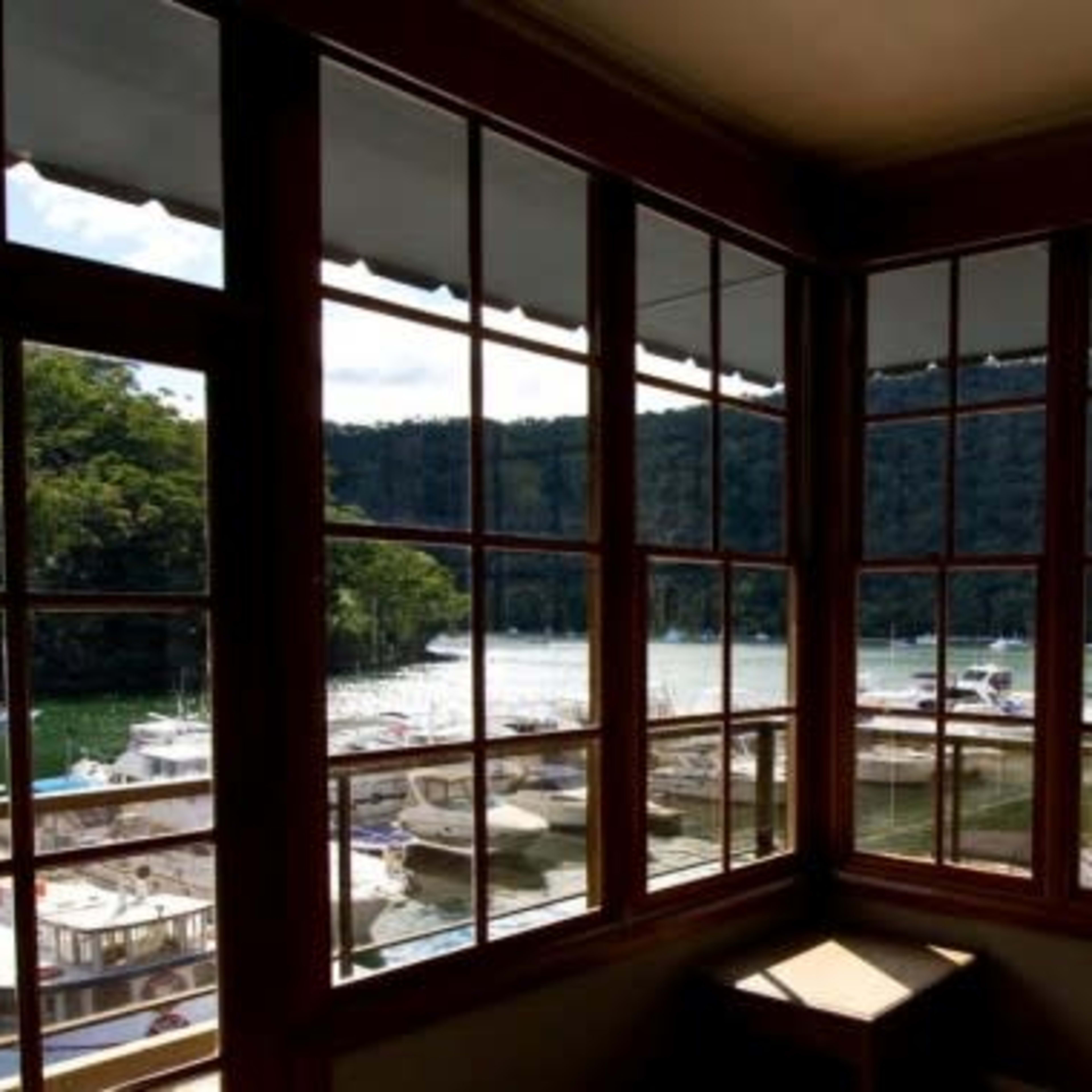 A view from a window overlooking a marina with boats docked along a green, wooded shoreline.