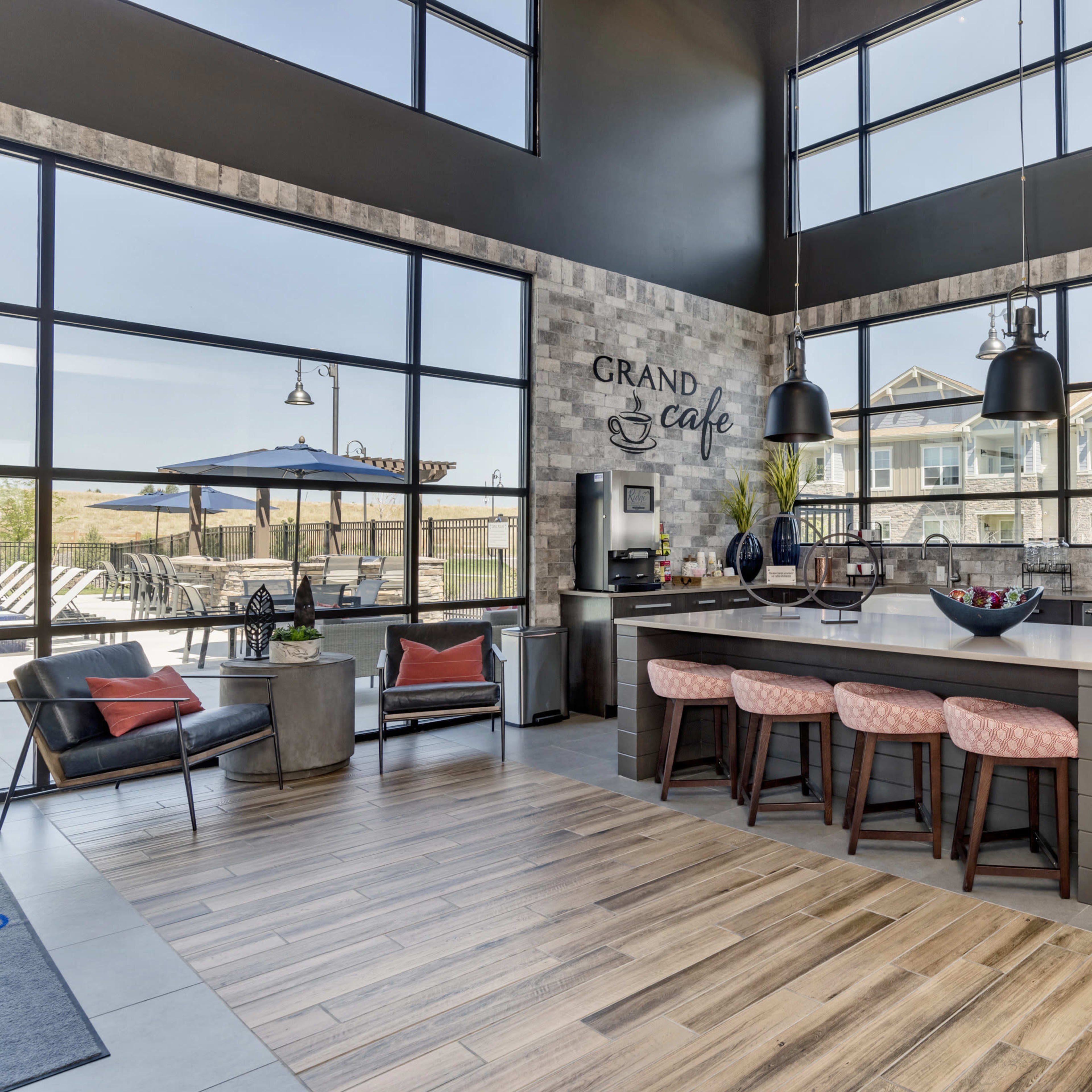 A modern café area with large windows, a central island bar with seating, and contemporary furnishings.
