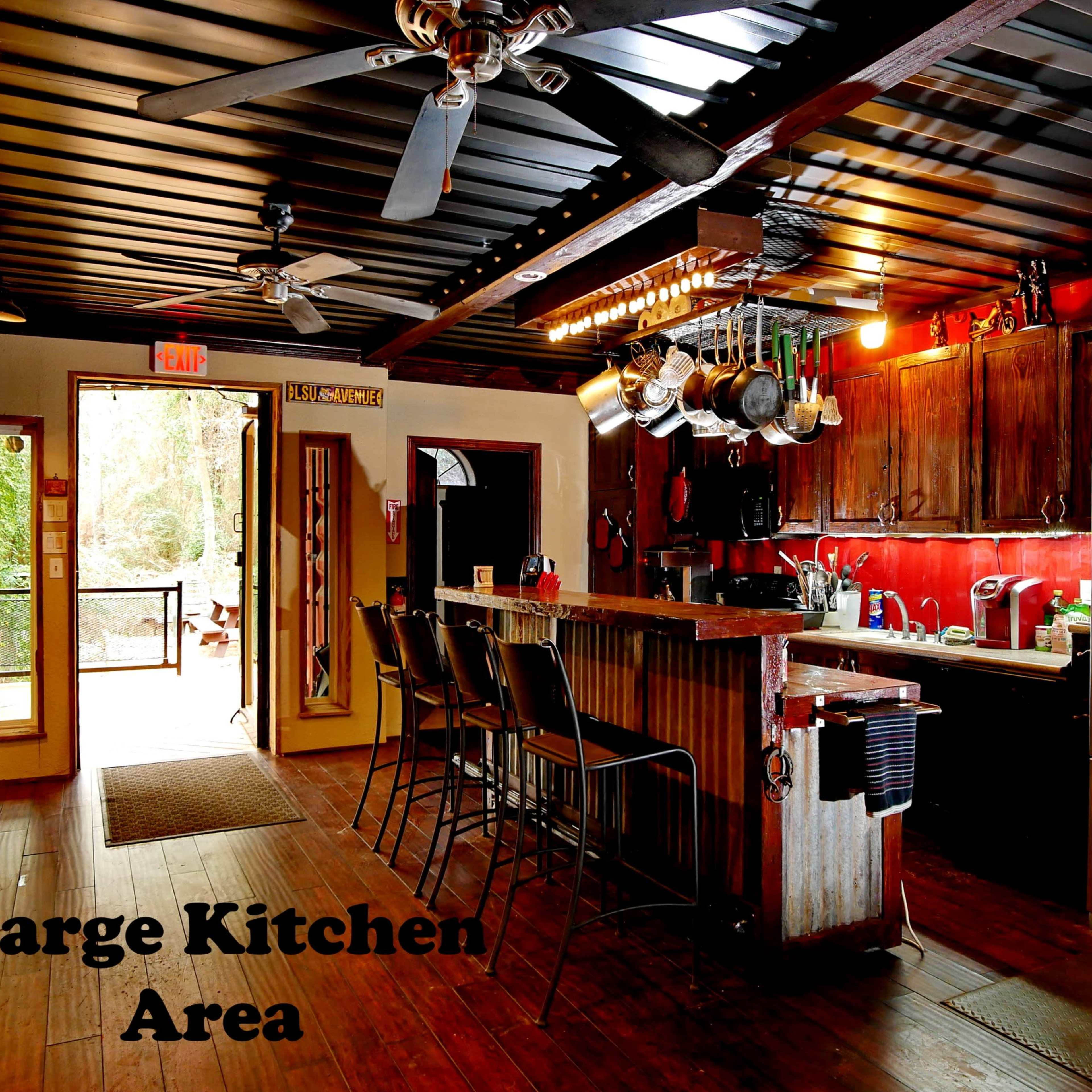 A spacious kitchen with wooden walls, stainless steel appliances, and a bar area with high stools.