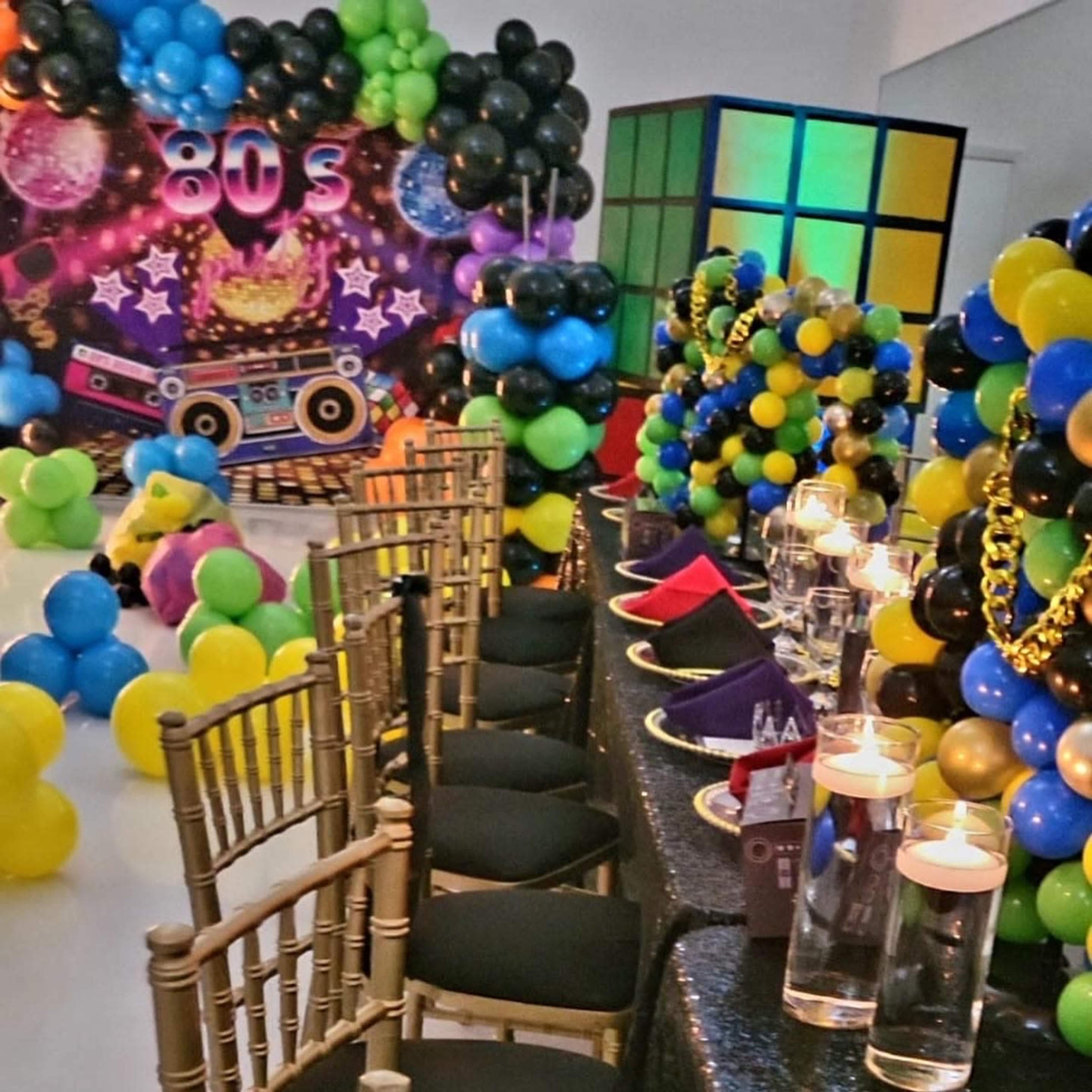A vibrant 80s-themed party setting with colorful balloons, geometric decor, and elegantly set tables.