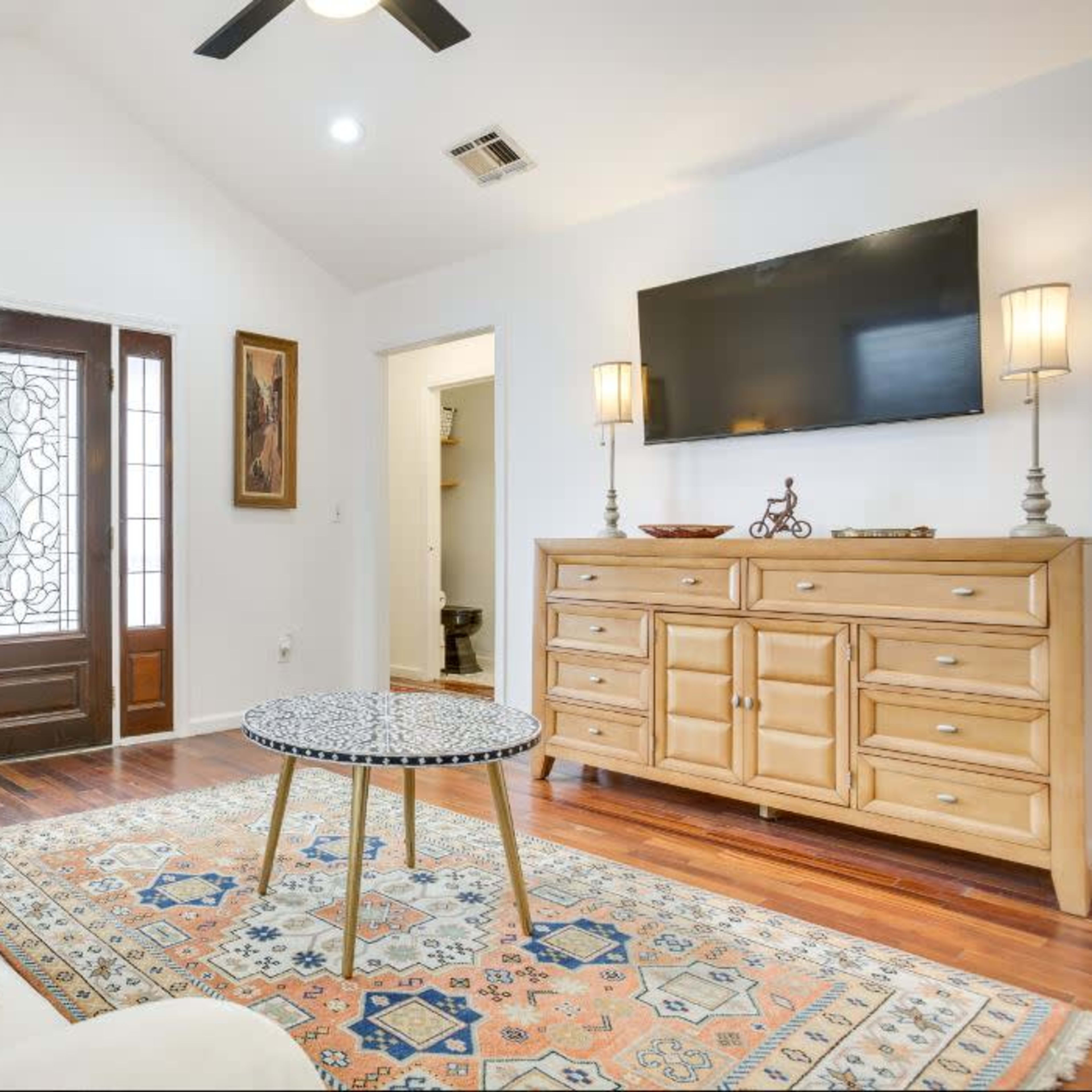 The room features a light-colored sofa, a decorative coffee table, and a wooden front door with glass panels.