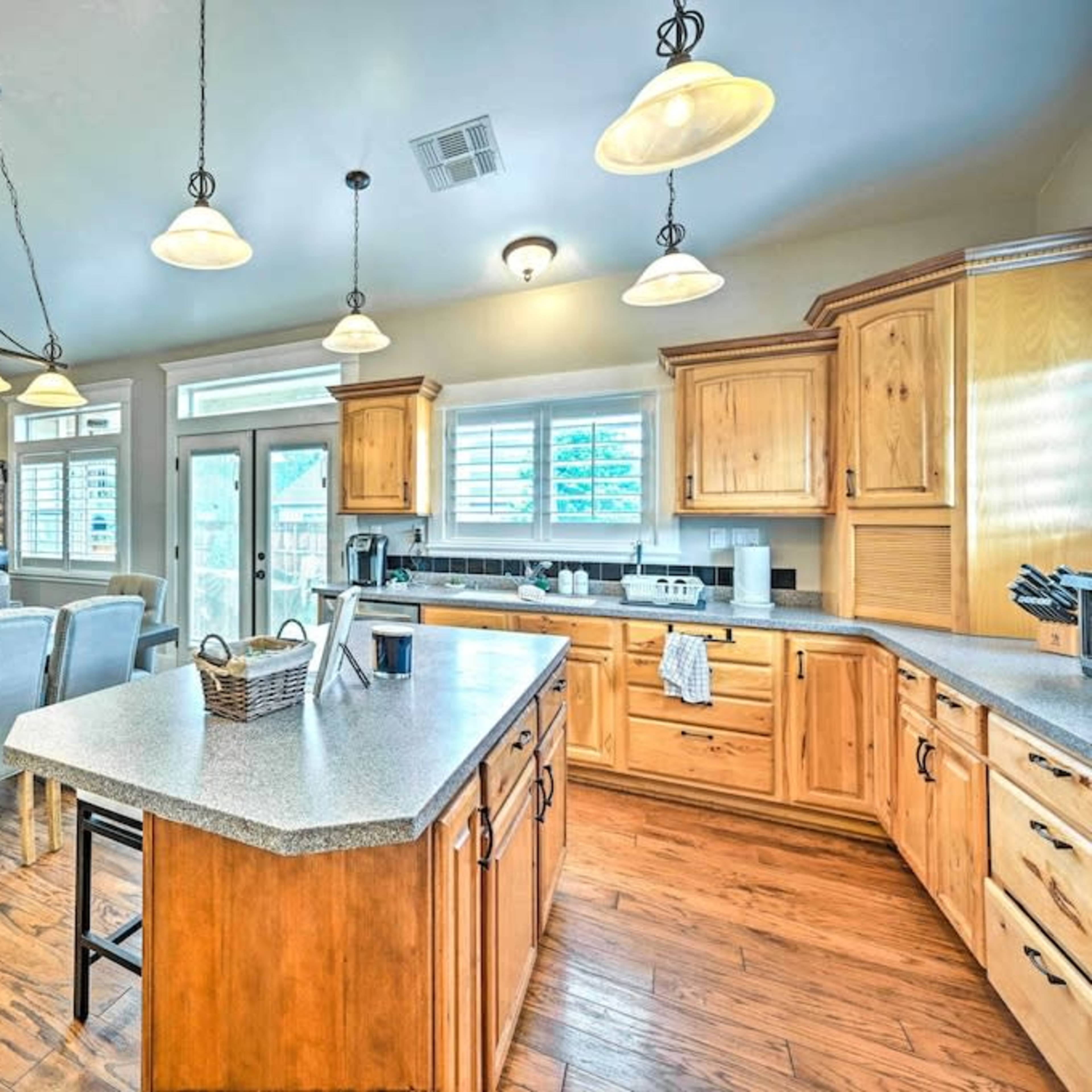A spacious kitchen with wooden cabinets, a central island, and a dining area adjacent to a living room, filled with natural light.