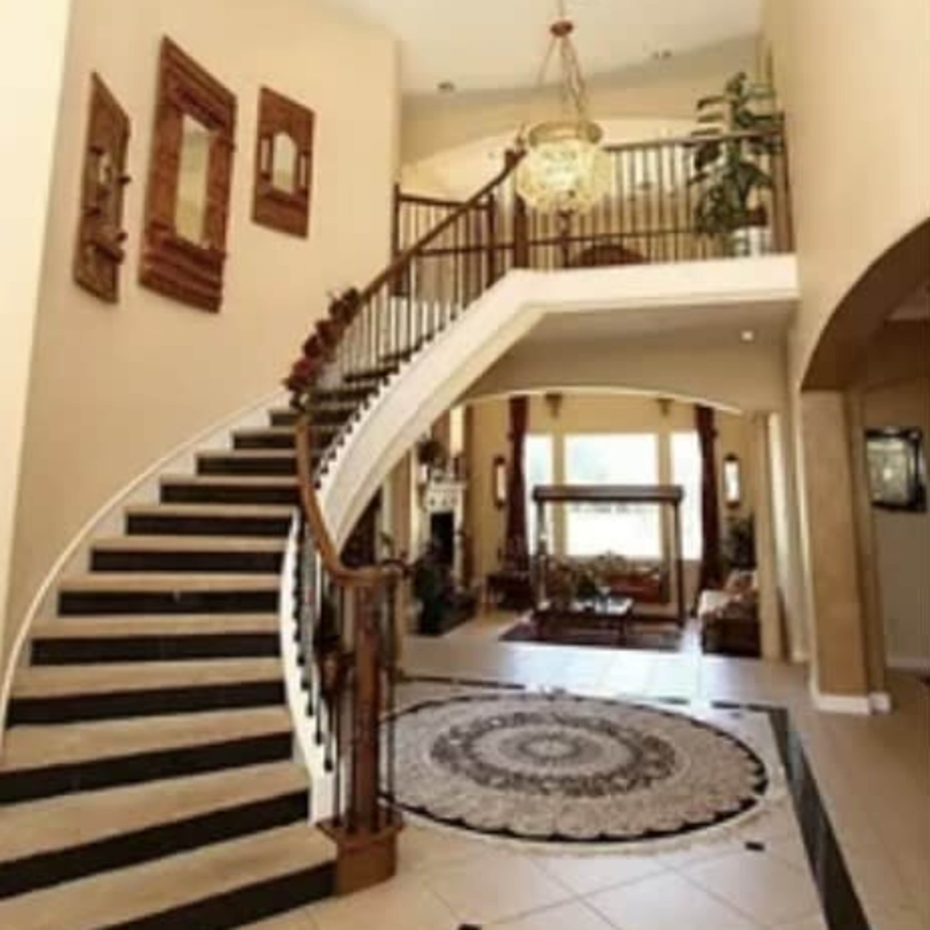 A spacious foyer with a curved staircase, a chandelier, and decorative elements on the walls.