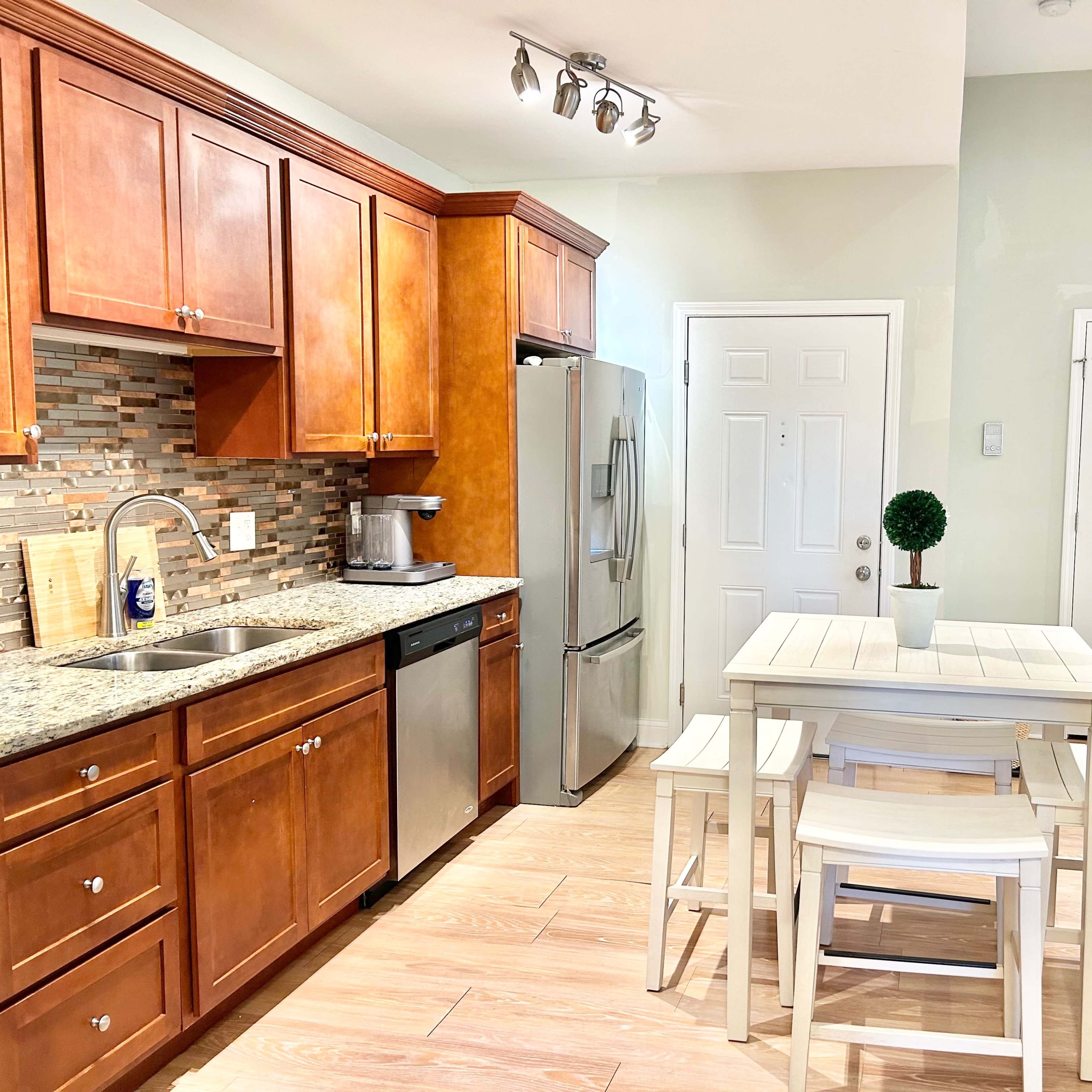 A modern kitchen with wooden cabinets, stainless steel appliances, and a small dining table set for four.