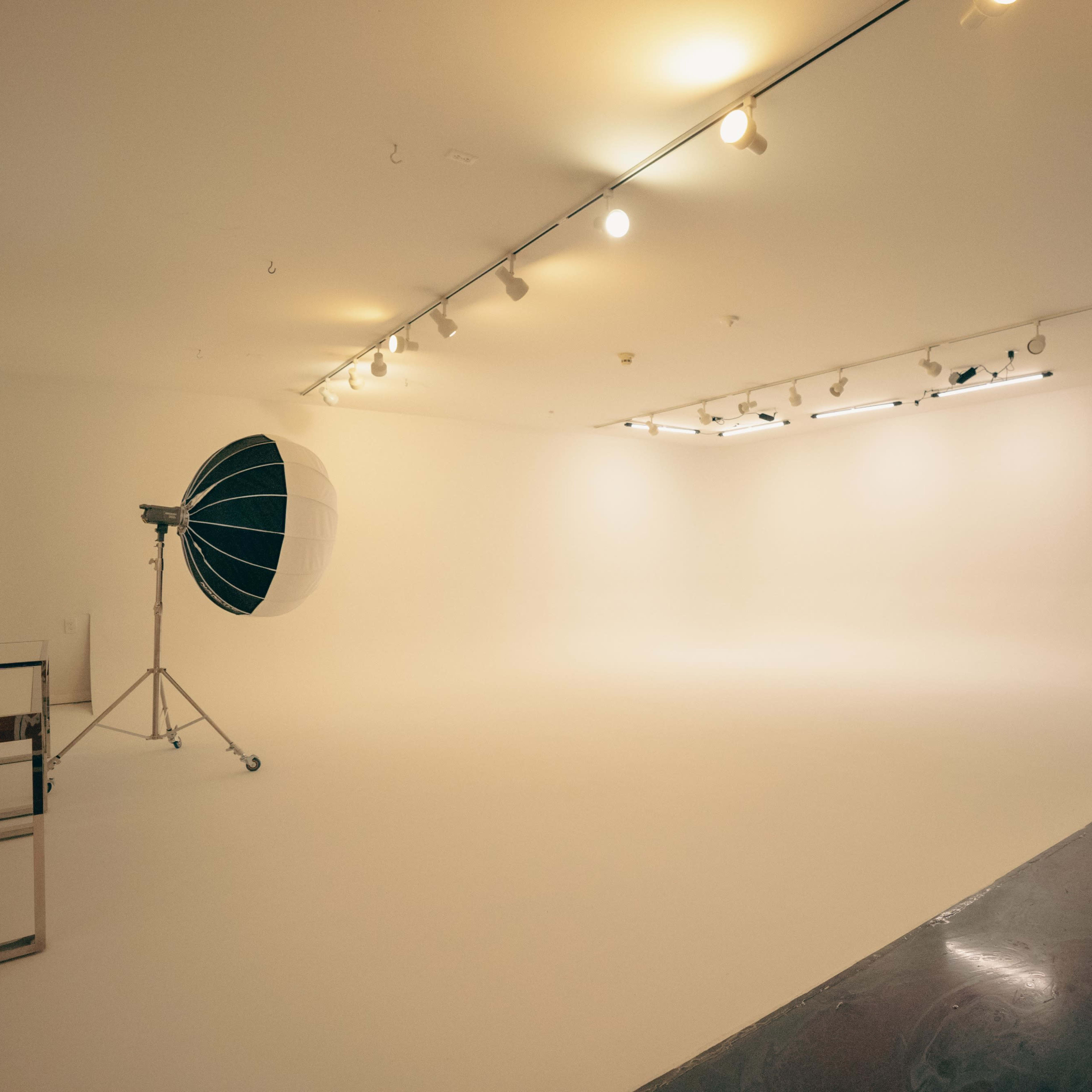 A spacious, well-lit photography studio with a large softbox and a seamless white backdrop.