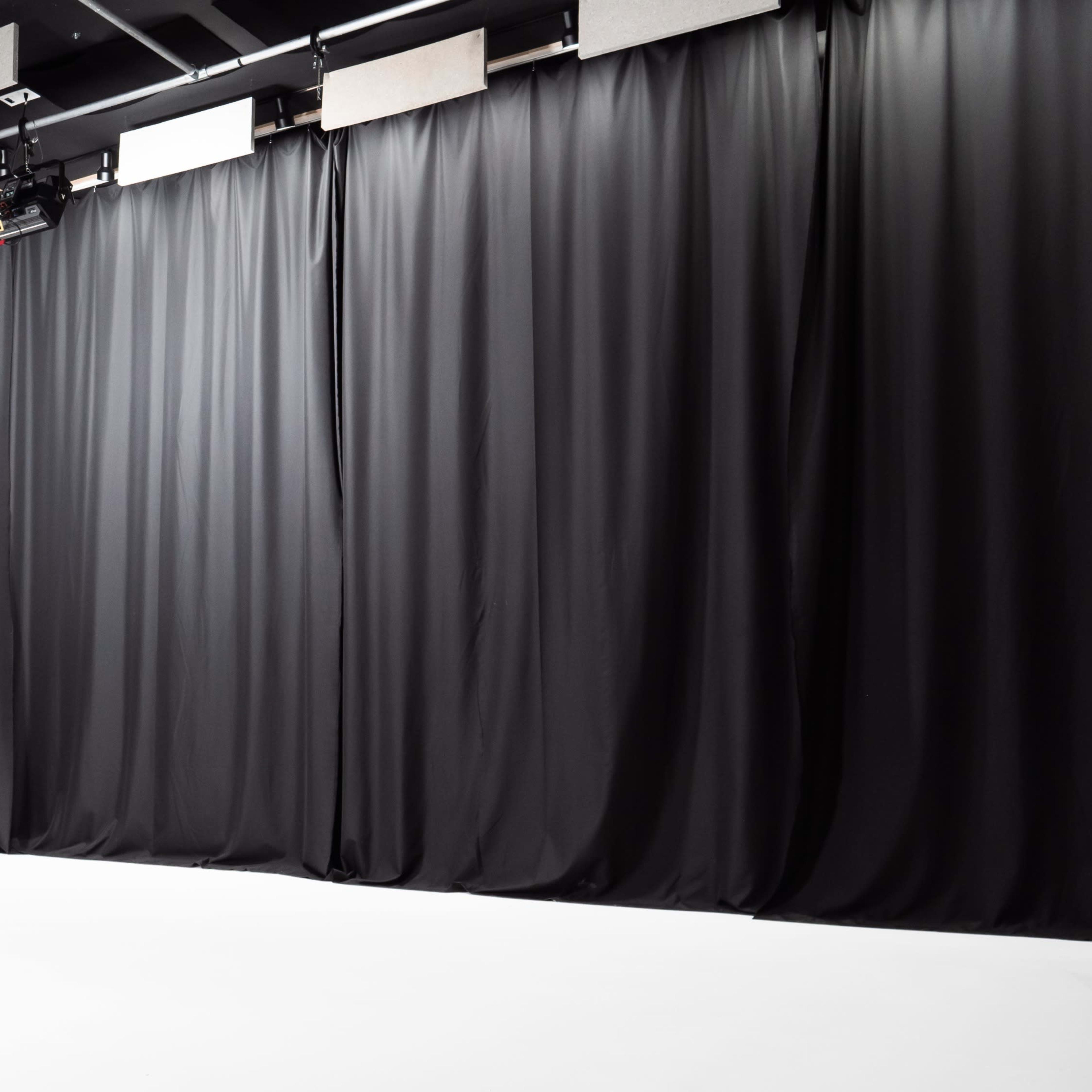 A photo studio with black curtains and a white floor.