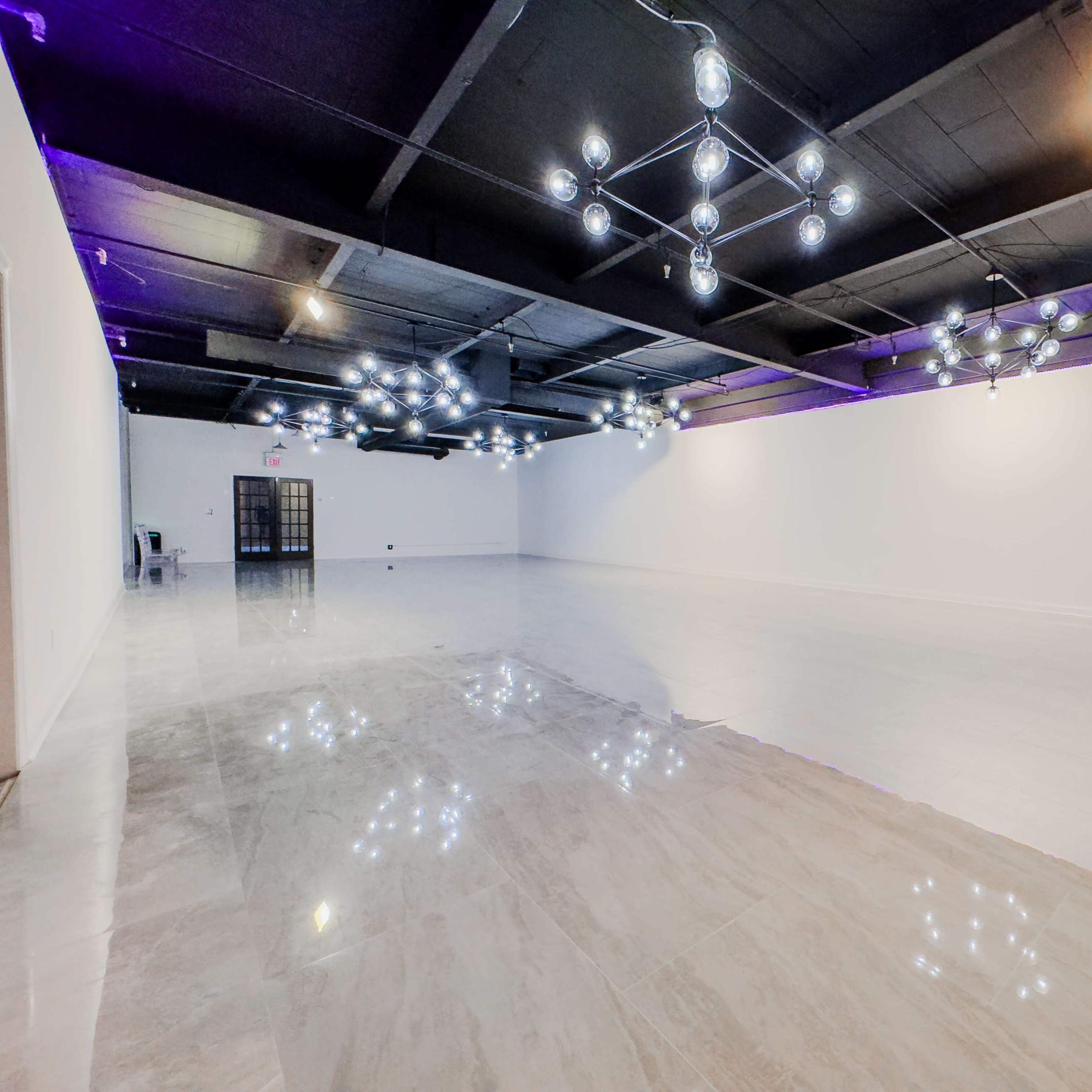 A spacious, well-lit room with polished marble floors and modern lighting fixtures hanging from the ceiling.