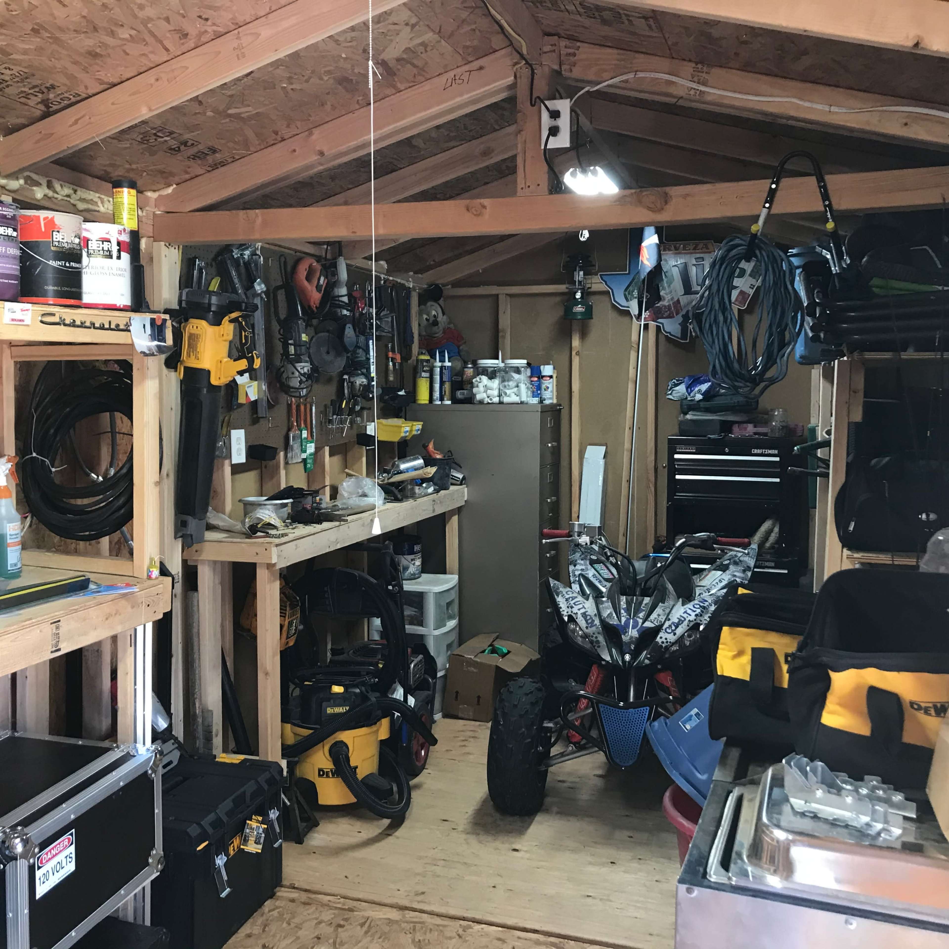 A cluttered workshop with various tools and equipment organized on shelves and hanging from the walls.