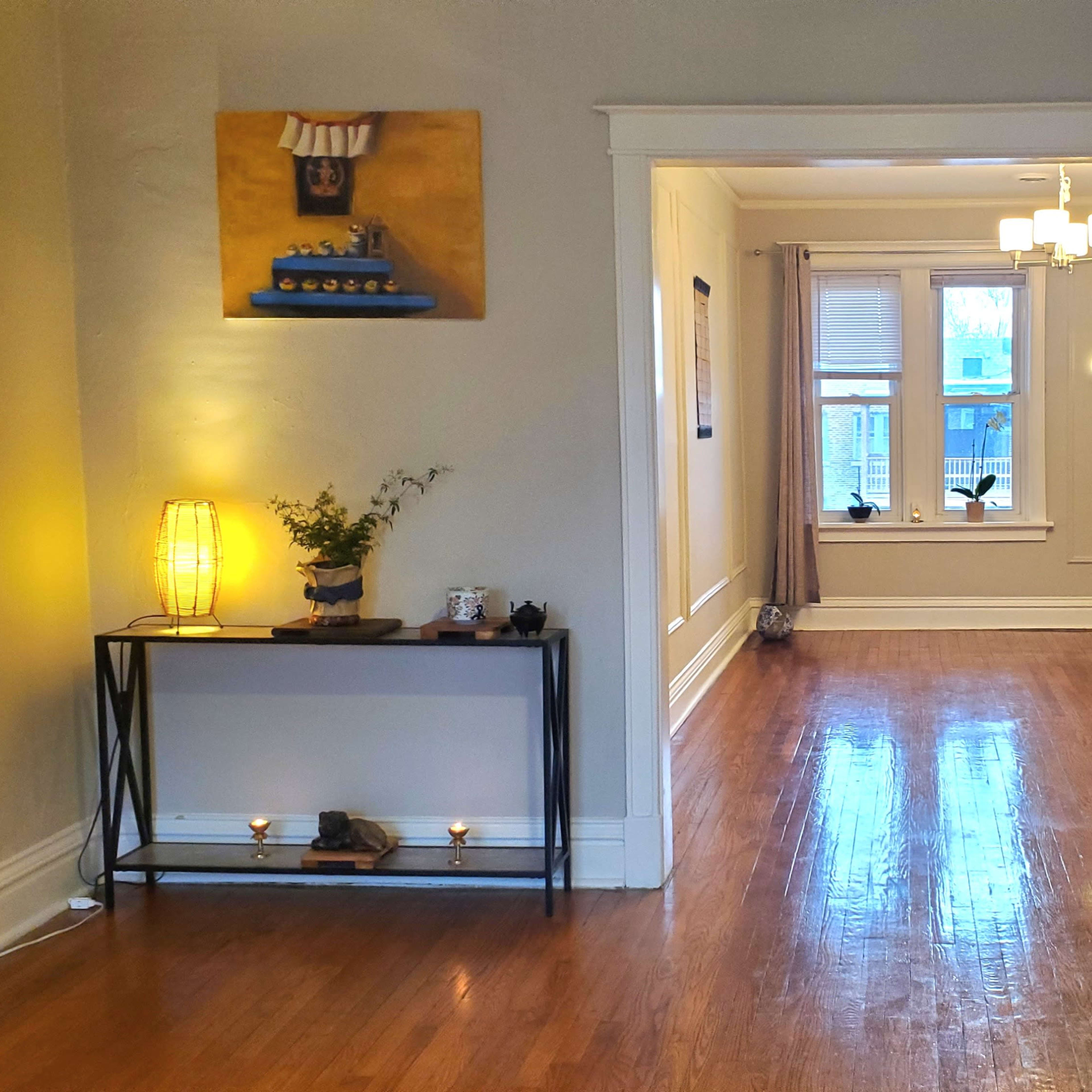 A spacious hallway leading to a well-lit room with wooden floors and decorative elements on the walls.