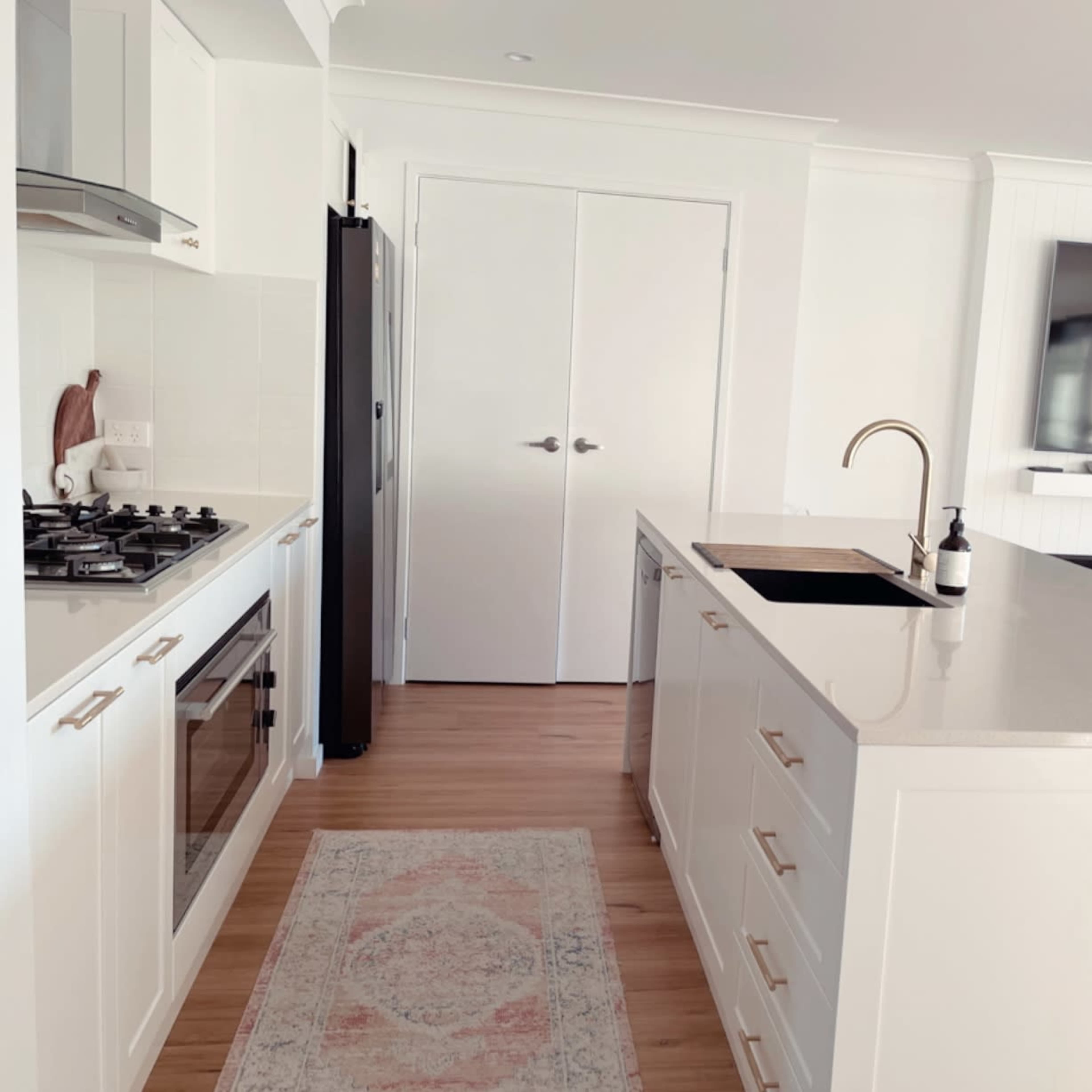 A modern kitchen with white cabinetry, a large island with a sink, and a gas stove.