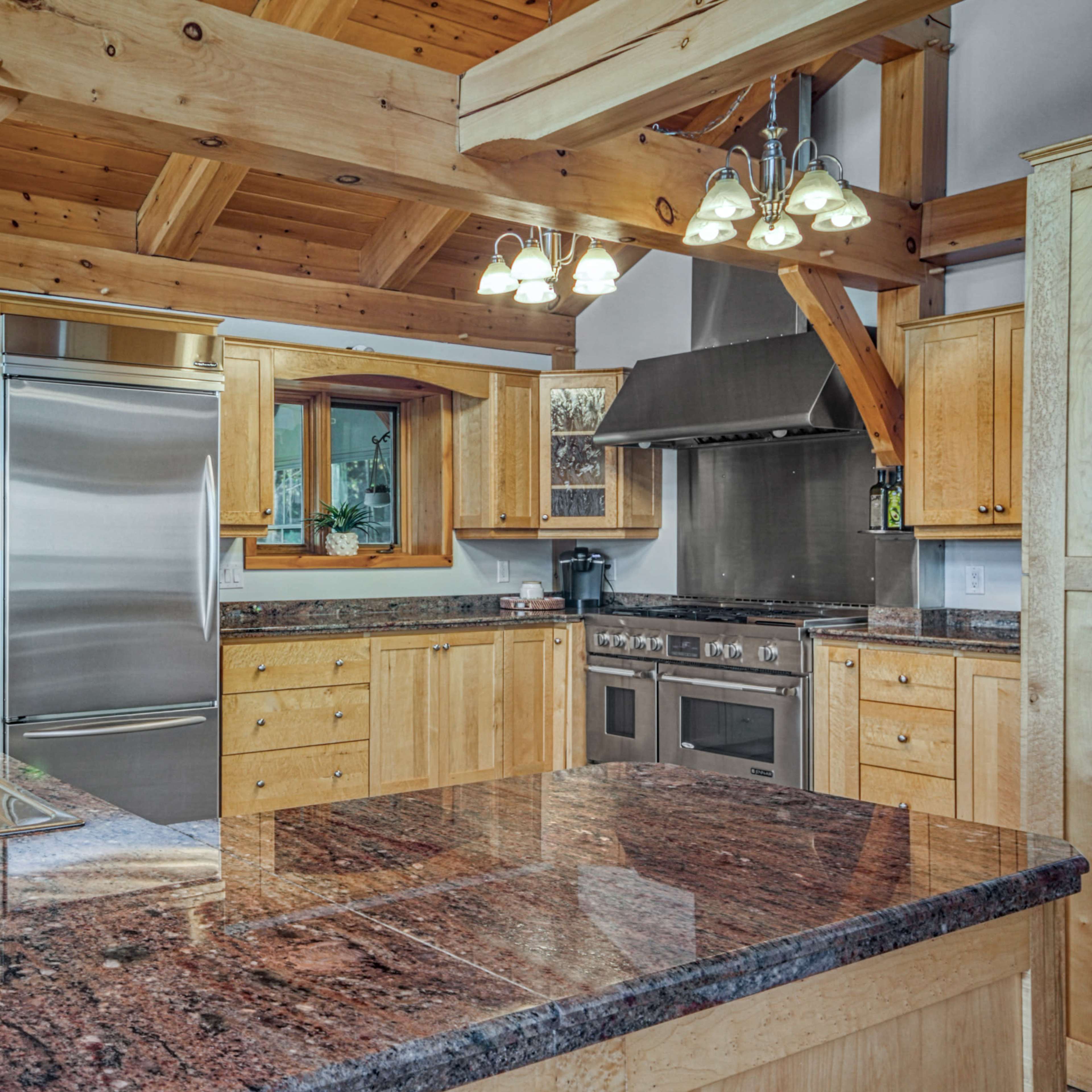 A modern kitchen with wooden beams, stainless steel appliances, and a granite countertop.